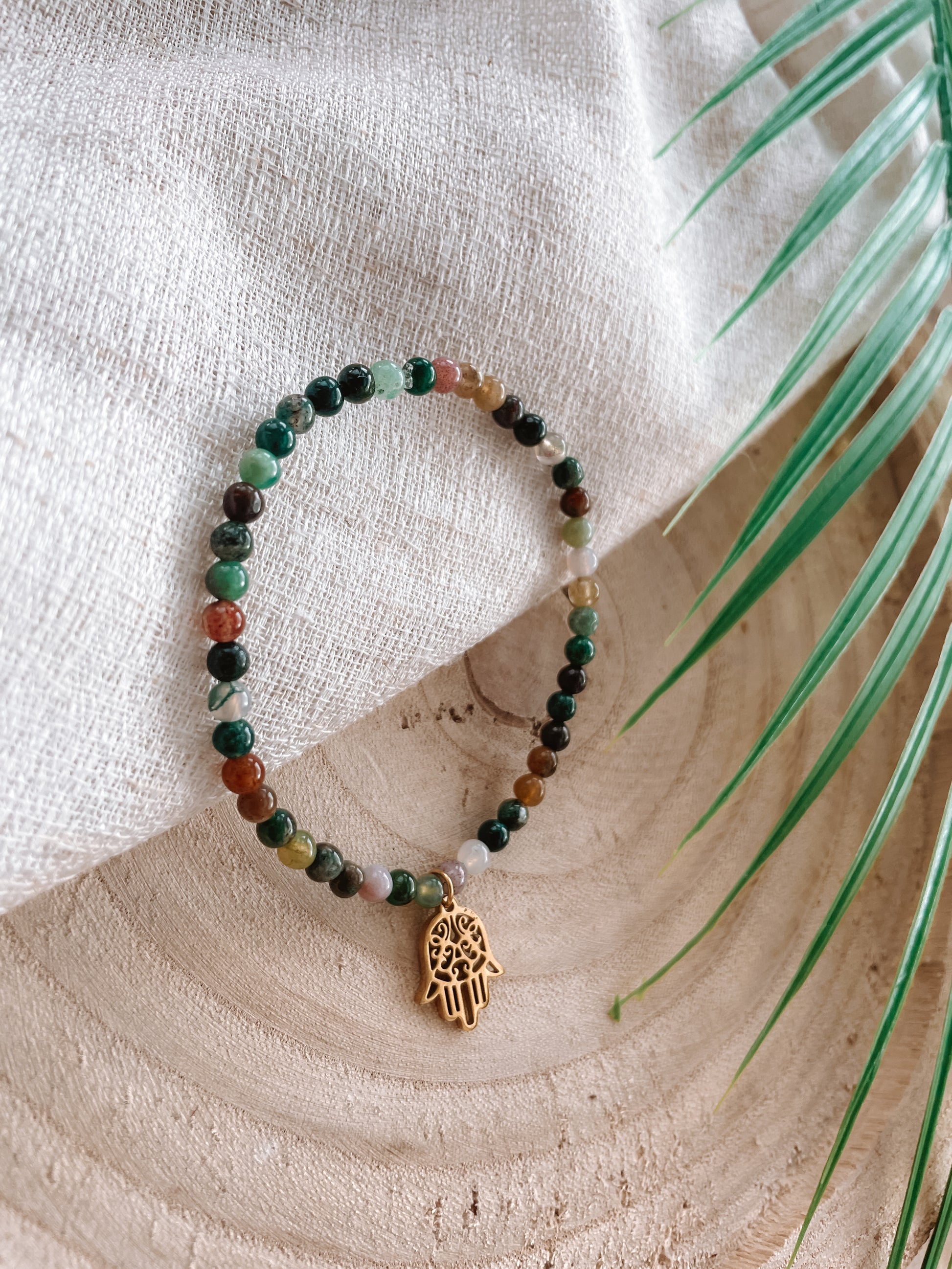 Buntes Turmalin-Perlenarmband mit goldenem Hand von Fatima Anhänger Anhänger liegend auf Tuch