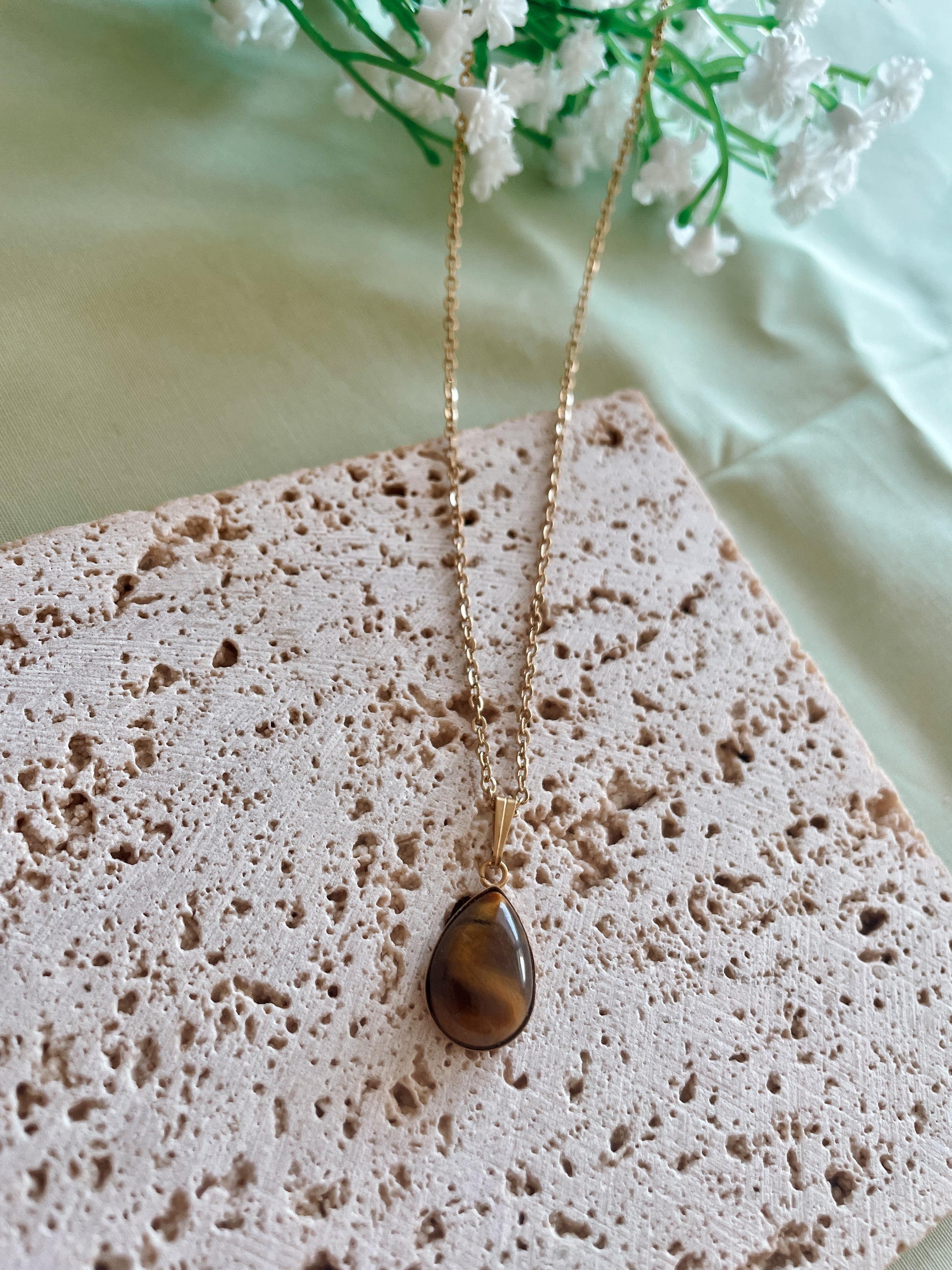 Handgemachte braune Tigerauge-Kette mit Tropfen Anhänger in Gold,  liegend auf Tablett