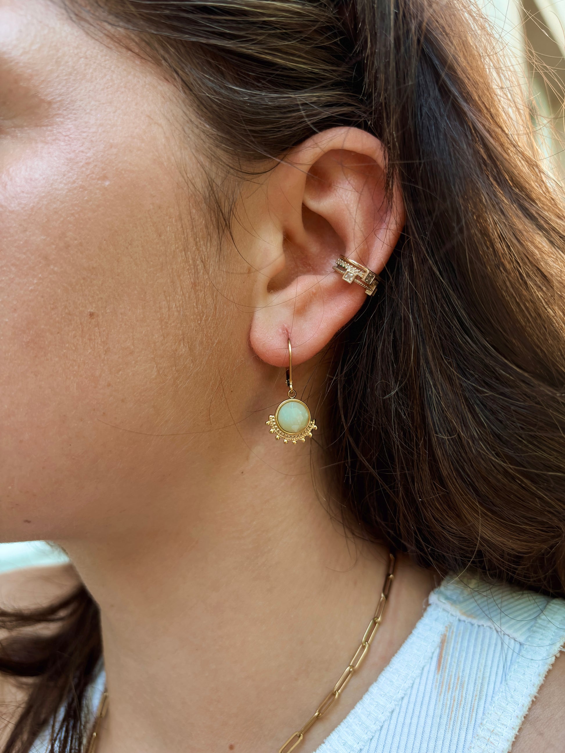 Ohrring mit goldenem verziertem Anhänger mit hellblauem Amazonit Stein am Ohr eines Modells