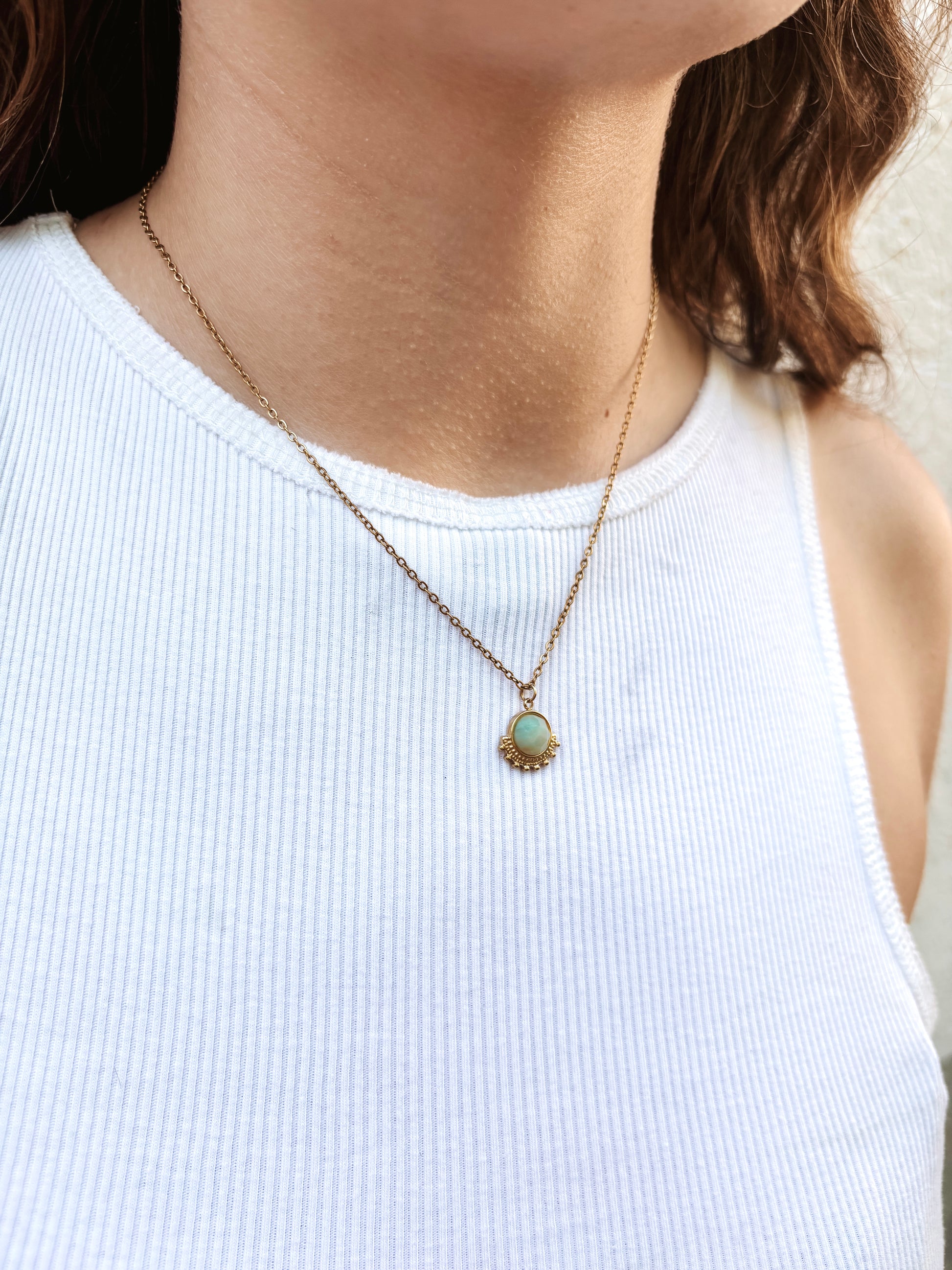Kette mit goldenem verziertem Anhänger mit türkisem Amazonit Stein am Hals eines Models