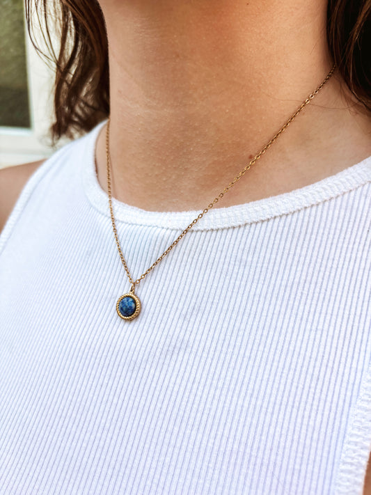 Kette mit goldenem rundem Anhänger mit blauem Lapislazuli Stein am Hals eines Models