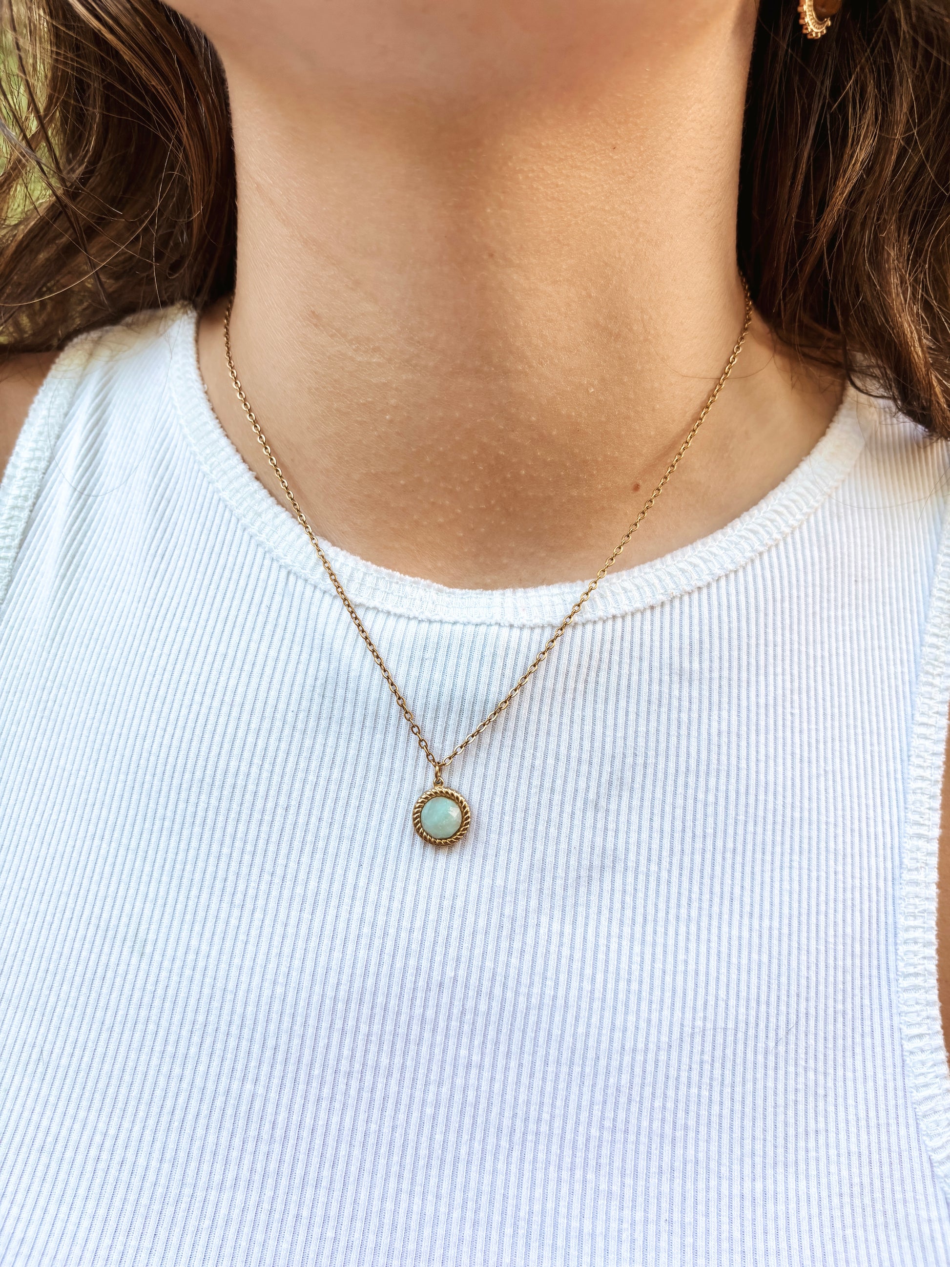 Kette mit goldenem facettiertem Anhänger mit blauem Amazonit Stein am Hals eines Models