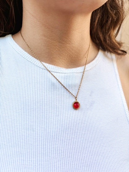 Kette mit goldenem rundem Anhänger mit rotem Rubin Stein am Hals eines Models