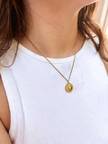 Kette mit goldenem Medaillon Anhänger mit hellblauem Larimar Stein am Hals eines Models