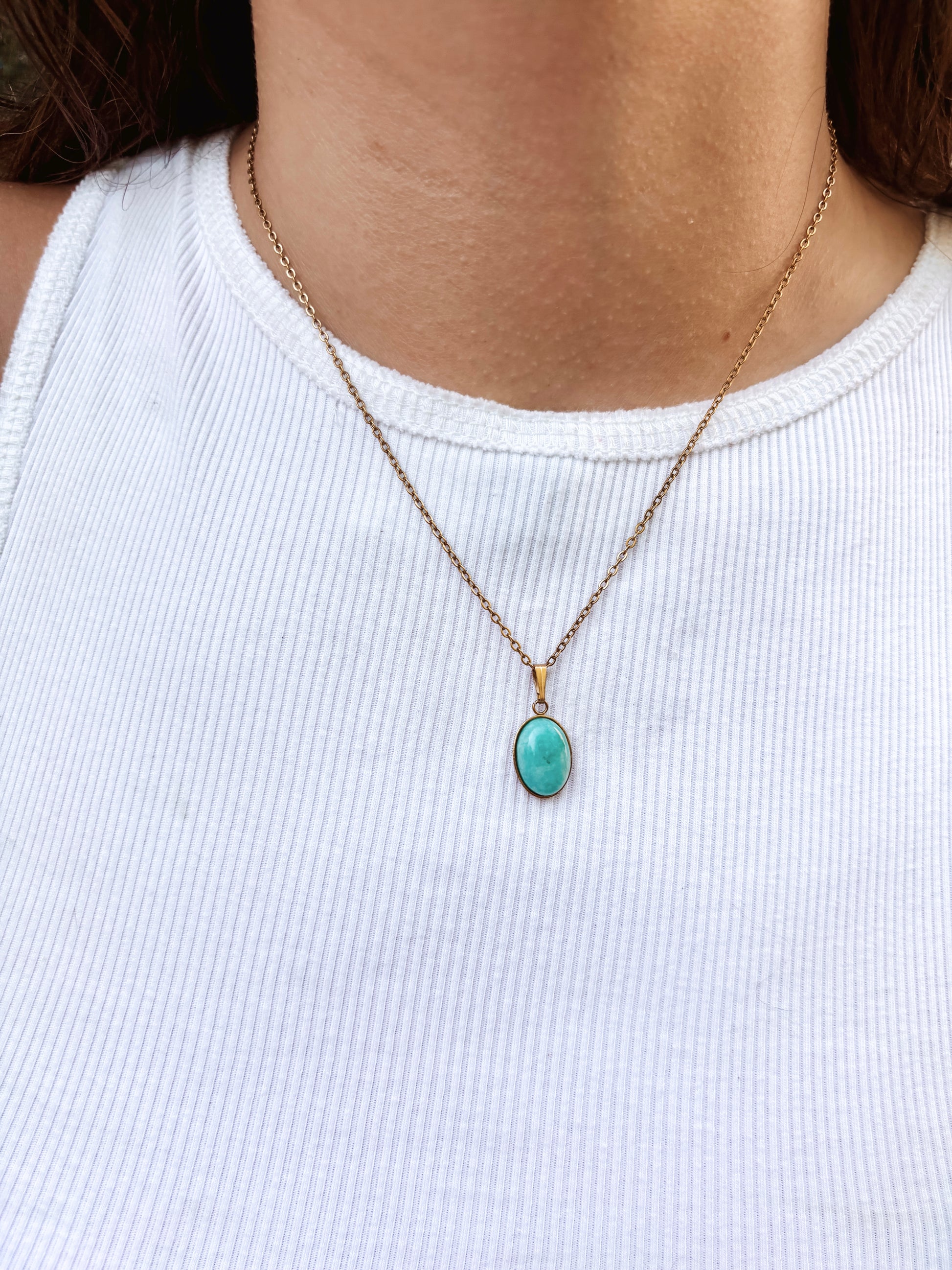 Kette mit goldenem ovalen Anhänger mit blauem Amazonit Stein am Hals eines Models