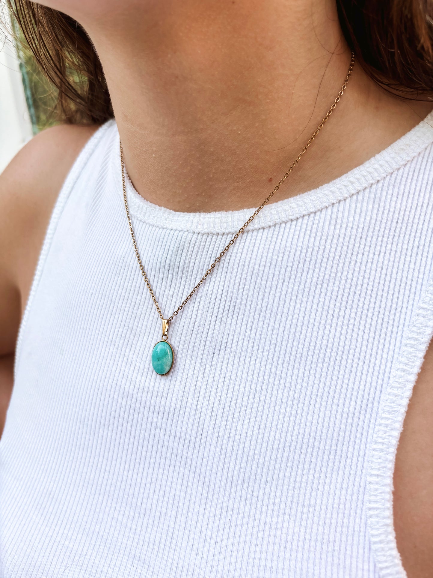 Kette mit goldenem ovalen Anhänger mit türkisem Amazonit Stein am Hals eines Models