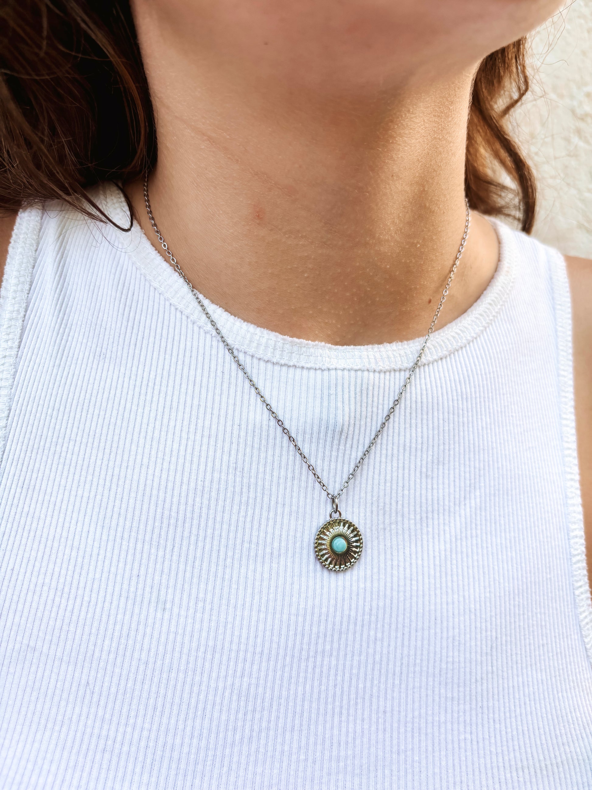 Kette mit silbernem verziertem Anhänger mit blauem Larimar Stein am Hals eines Models