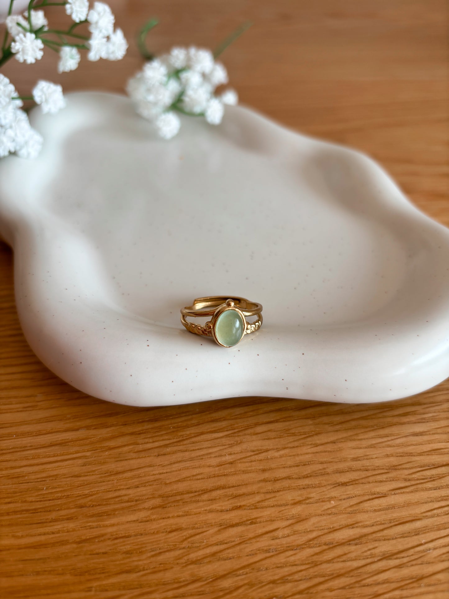 Goldring mit ovalem grünen Aventurin-Stein auf Tablett