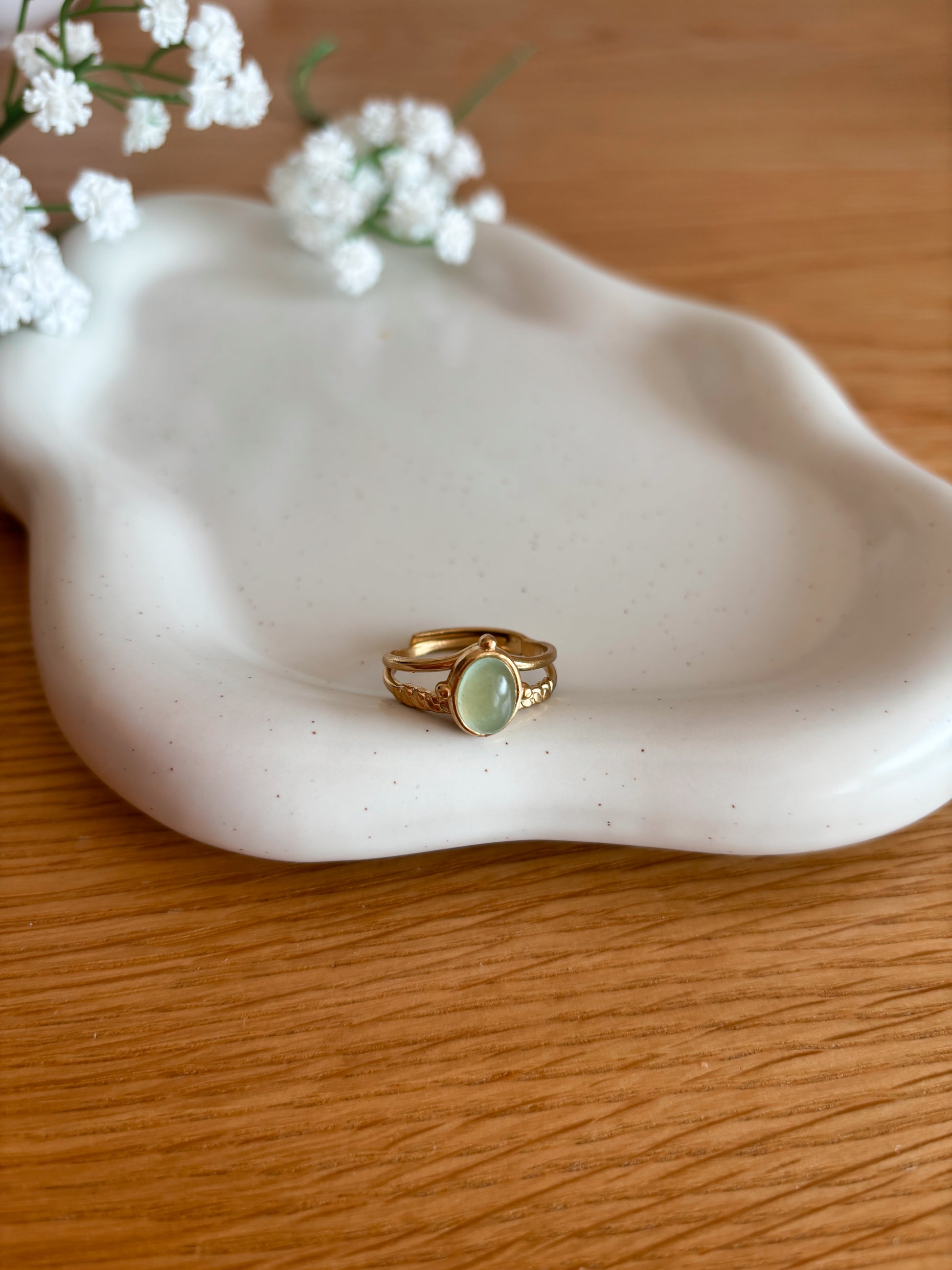 Goldring mit ovalem grünen Aventurin-Stein auf Tablett