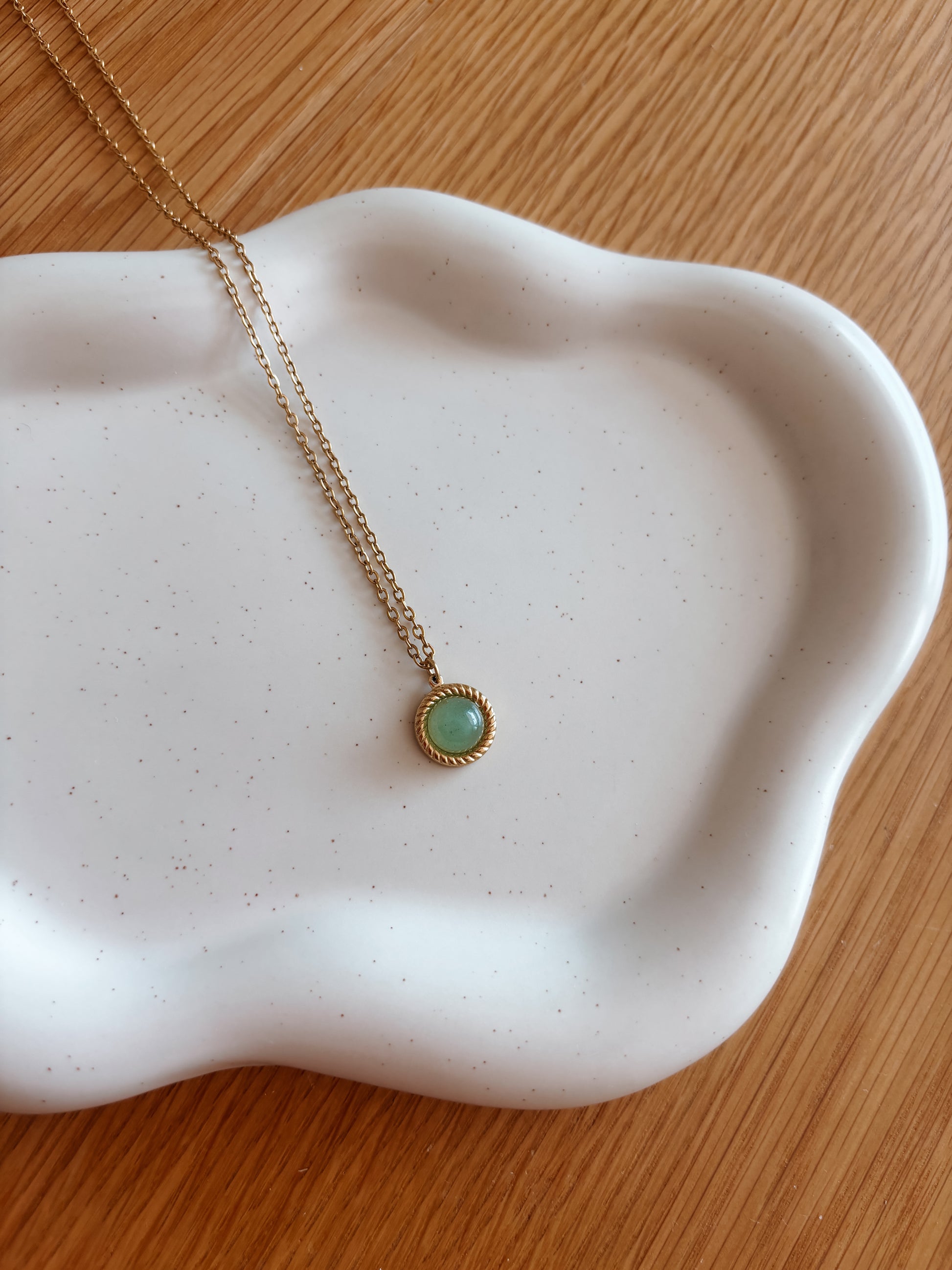 Handgemachte grüne Aventurin-Kette mit rundem Anhänger in Gold,  liegend auf Tablett