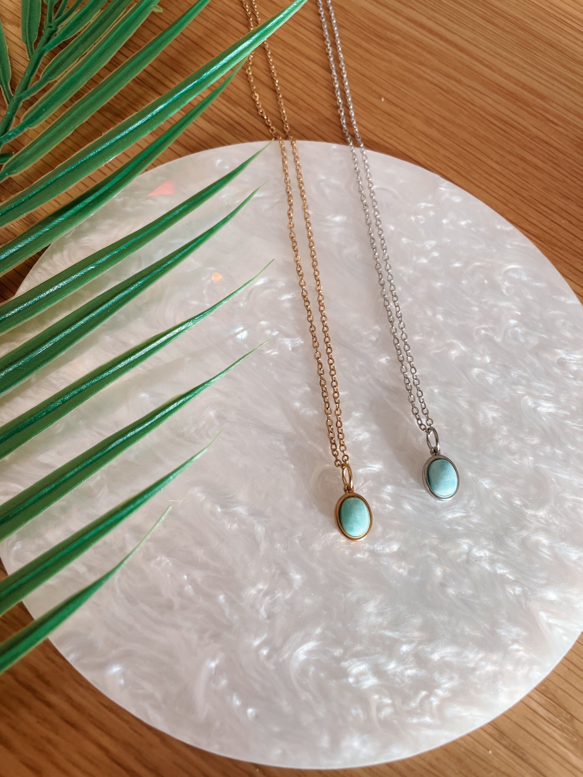 Handgemachte hellblaue Larimar-Ketten mit ovalem Anhänger in Gold und Silber, liegend auf Tablett