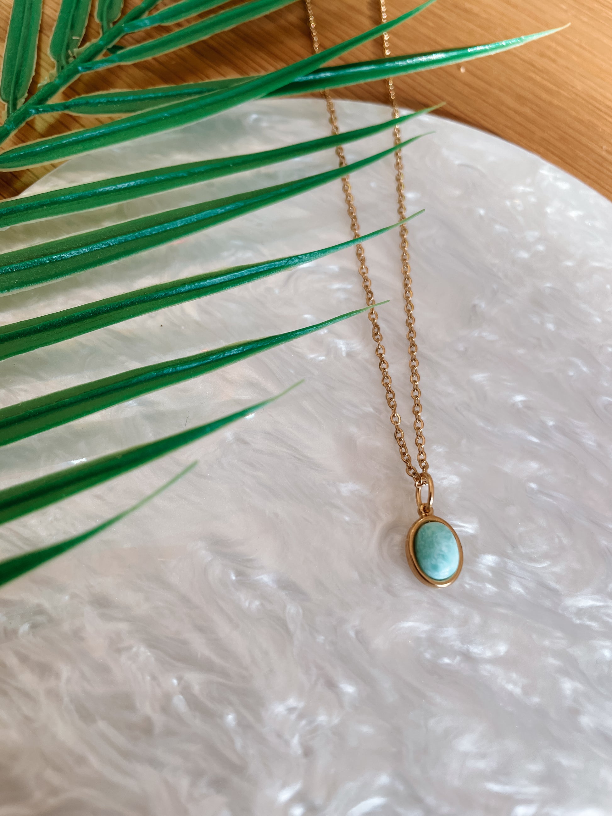 Handgemachte hellblaue Larimar-Kette mit ovalem Anhänger in Gold,  liegend auf Tablett