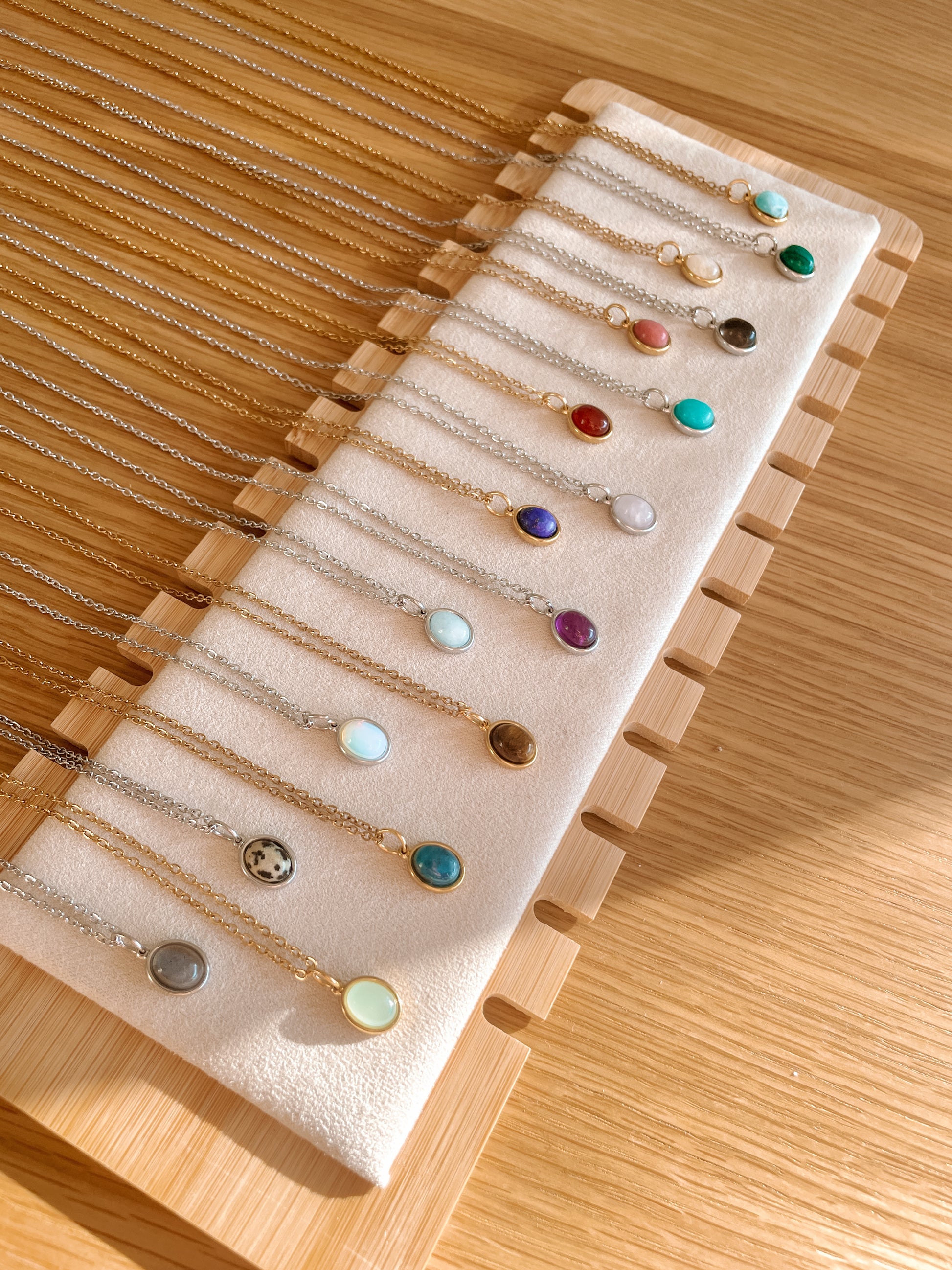 Handgemachte bunte Edelstein-Ketten mit ovalem Anhänger in Gold und Silber, liegend auf Tablett, Ansicht von oben