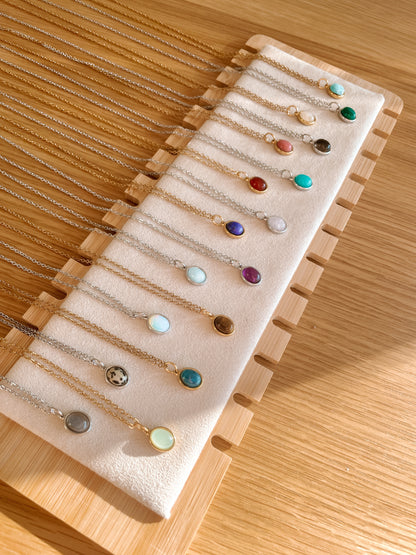 Handgemachte bunte Edelstein-Ketten mit ovalem Anhänger in Gold und Silber, liegend auf Tablett, Ansicht von oben