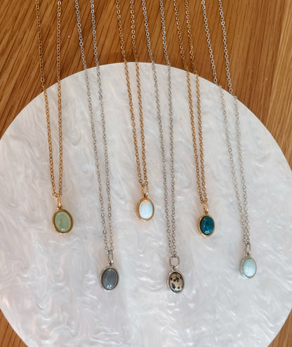 Handgemachte Edelstein-Ketten mit ovalem Anhänger in Gold und Silber, liegend auf Tablett.
