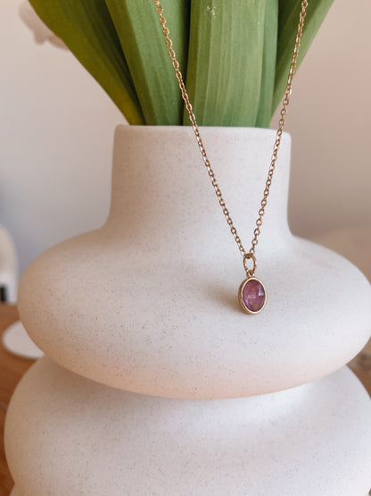 Handgemachte lila Amethyst-Kette mit ovalem Anhänger in Gold, hängend an einer Vase
