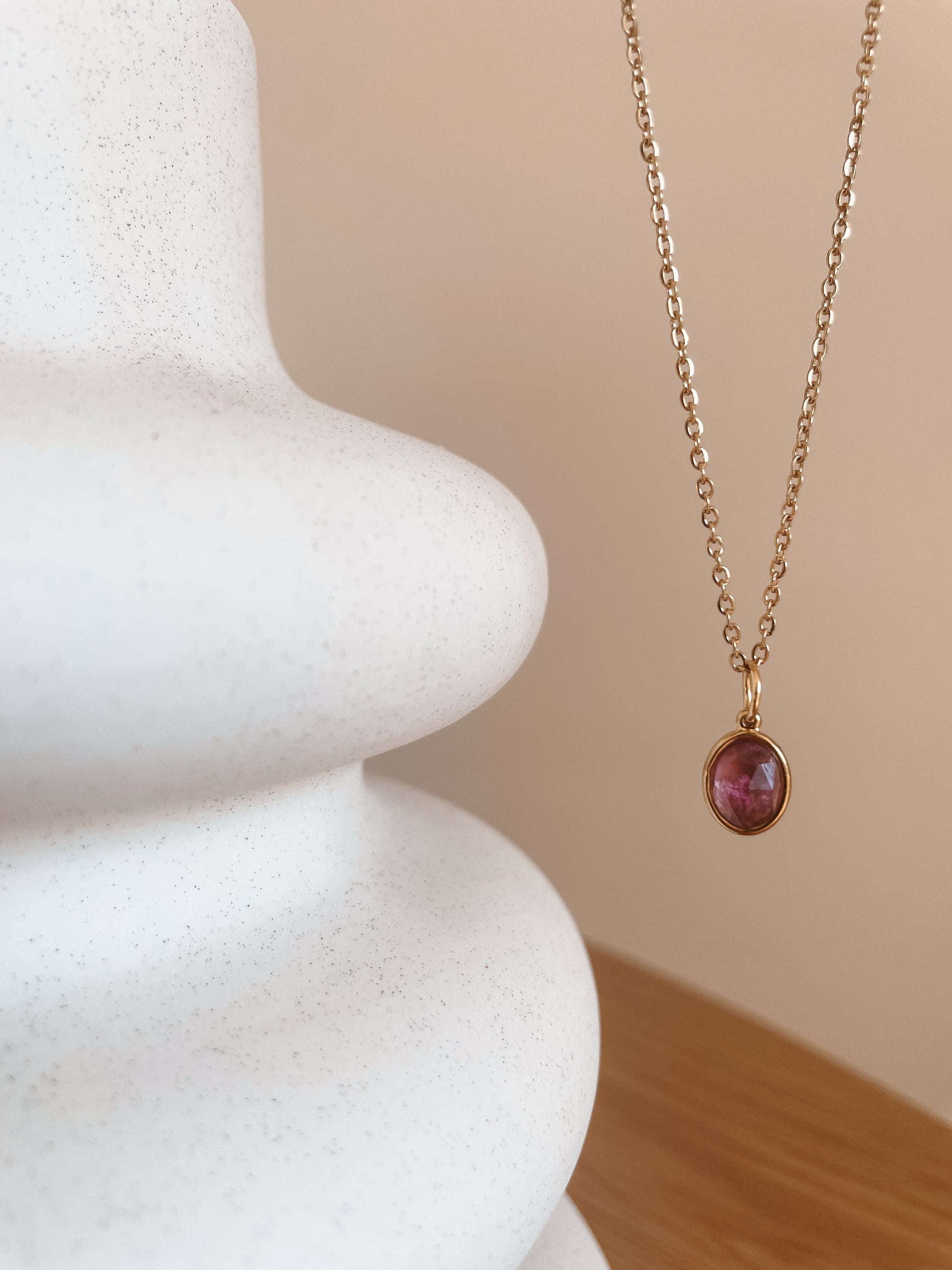 Handgemachte lila Amethyst-Kette mit ovalem facettierten Anhänger in Gold, hängend an einer Vase