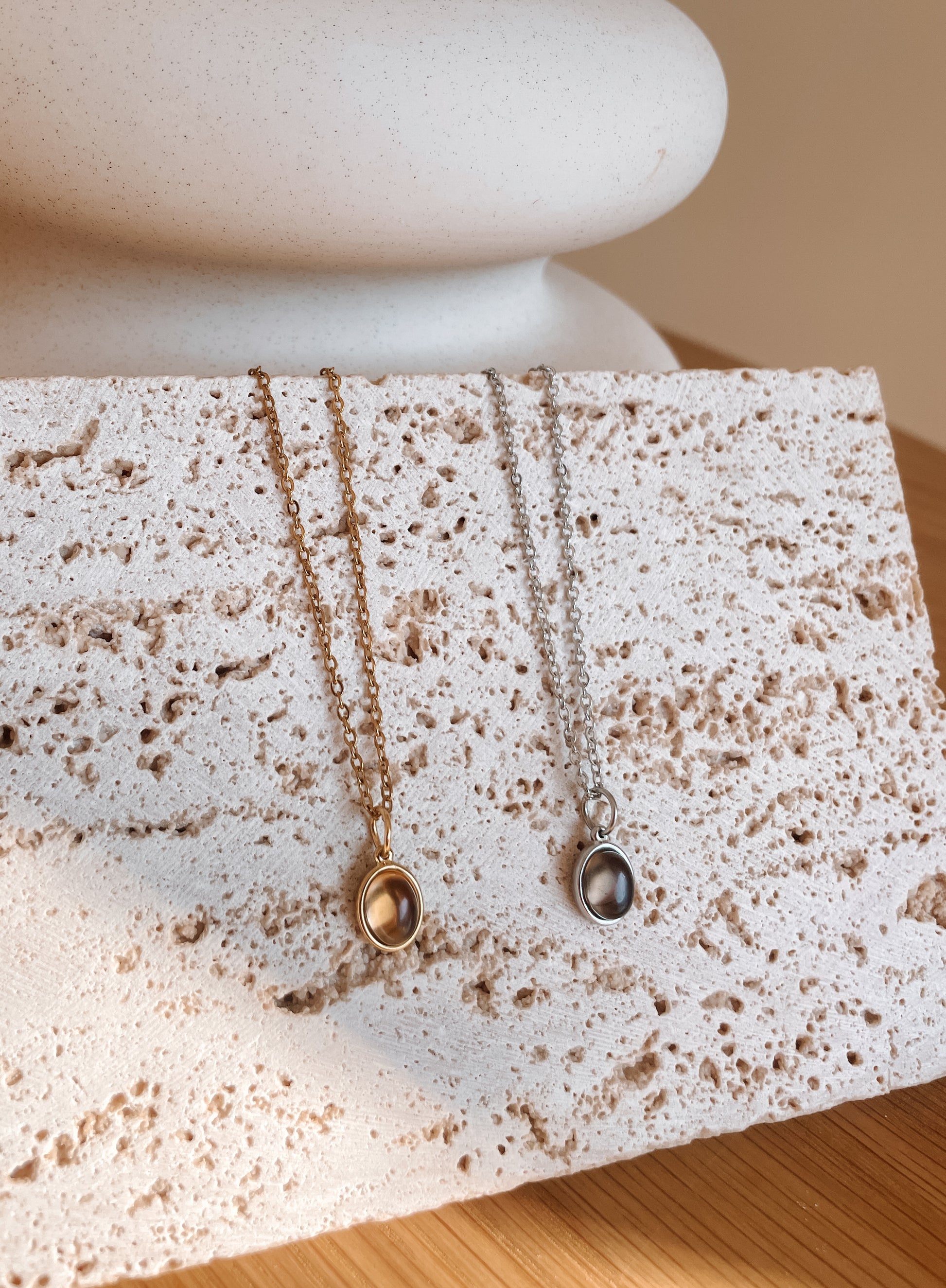 Handgemachte braune Rauchquarz-Ketten mit ovalem Anhänger in Gold und Silber, hängend an Steinplatte