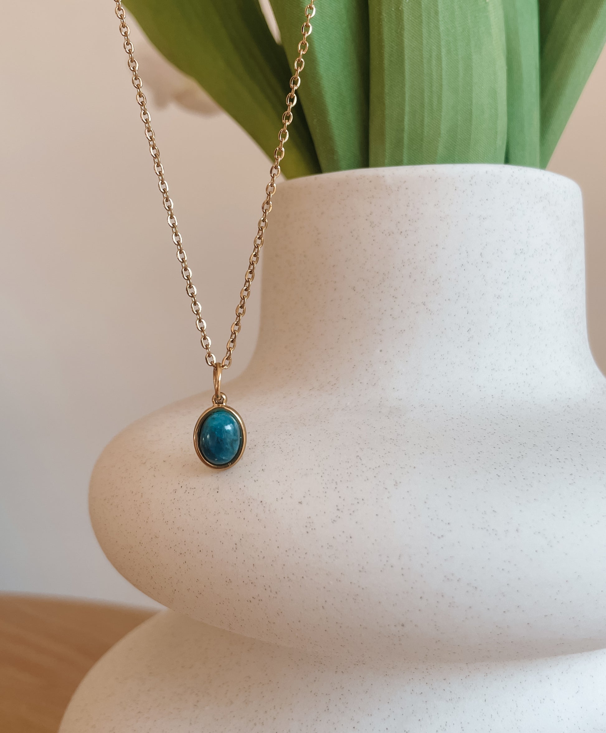 Handgemachte blaue Apatit-Kette mit ovalem Anhänger in Gold, hängend an einer Vase