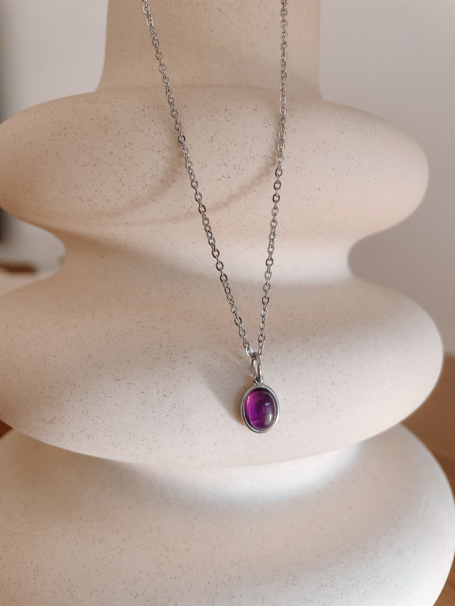 Handgemachte lila Amethyst-Kette mit ovalem Anhänger in Silber, hängend an einer Vase