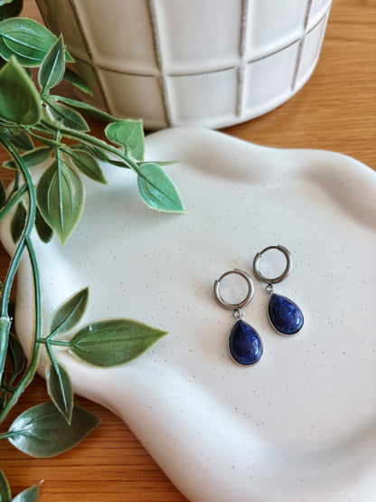 Silberne Creolen-Ohrringe mit tropfenförmigen, blauen Lapislazuli-Steinen auf Tablett