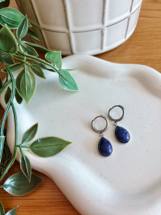Silberne Creolen-Ohrringe mit tropfenförmigen, blauen Lapislazuli-Steinen auf Tablett