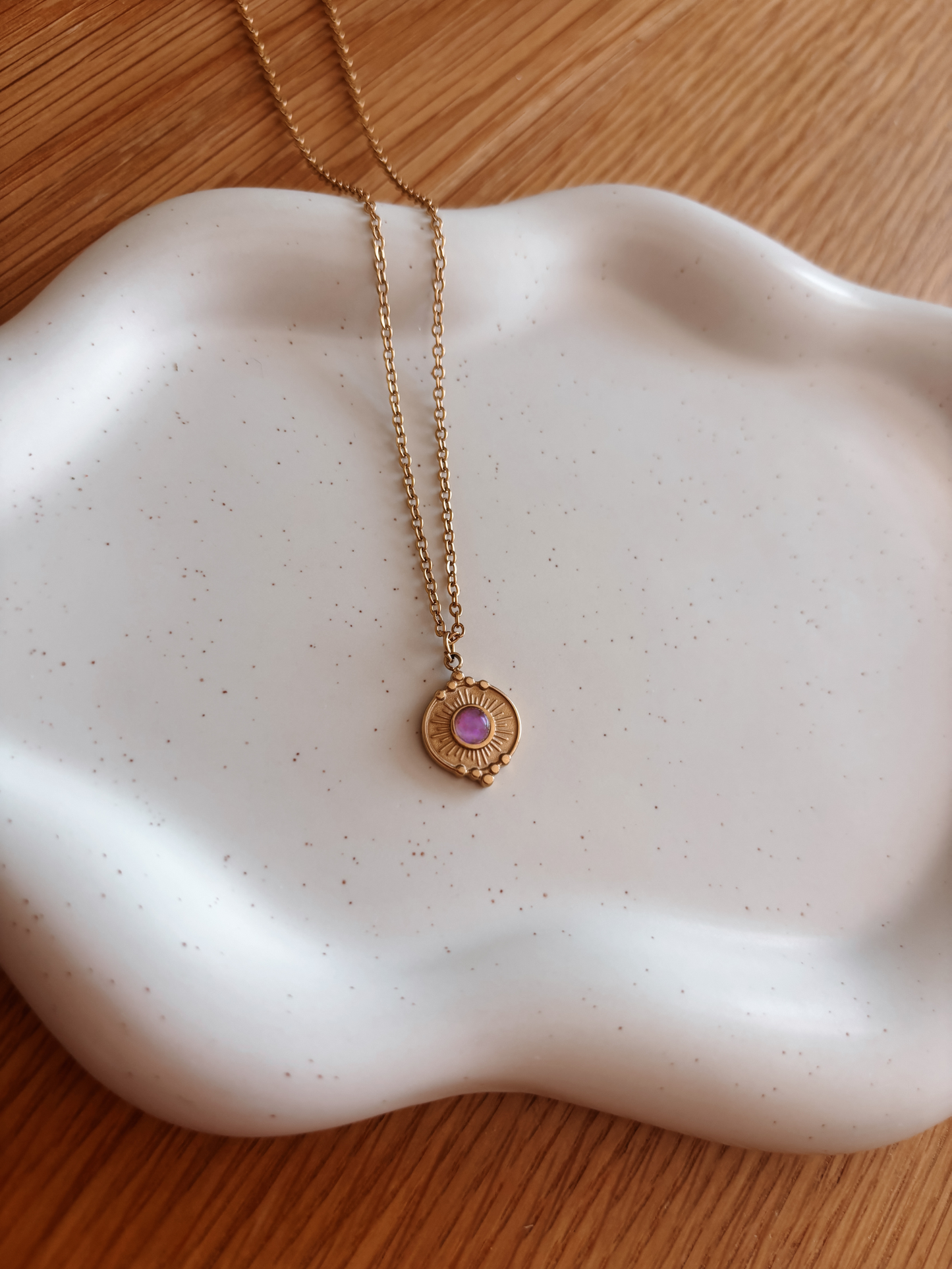Handgemachte lila Amethyst-Kette mit rundem Münze Anhänger in Gold,  liegend auf Tablett