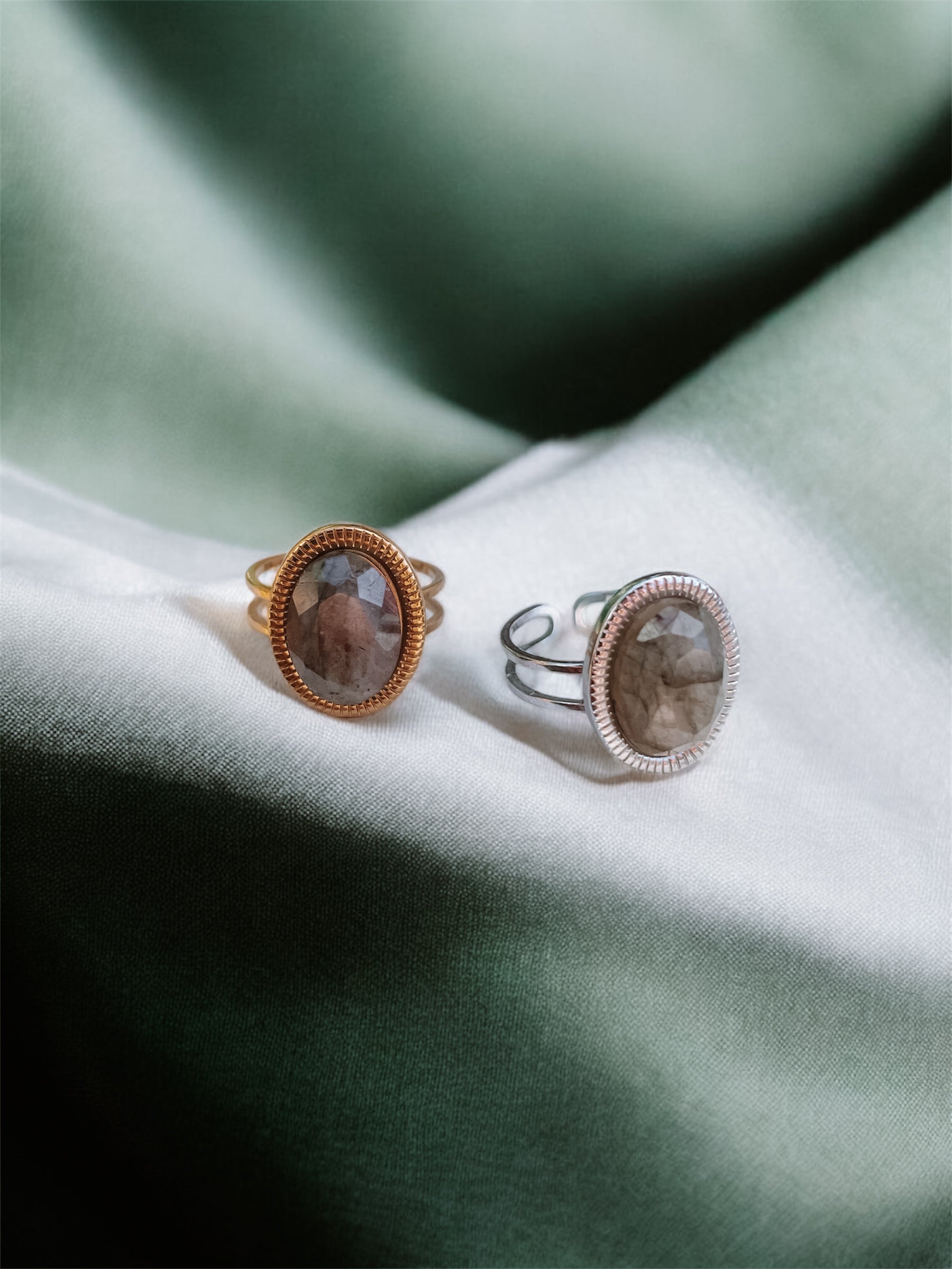 Ringe in Gold und Silber mit ovalem grün-grauen Labradorit-Steinen auf grünem Tuch