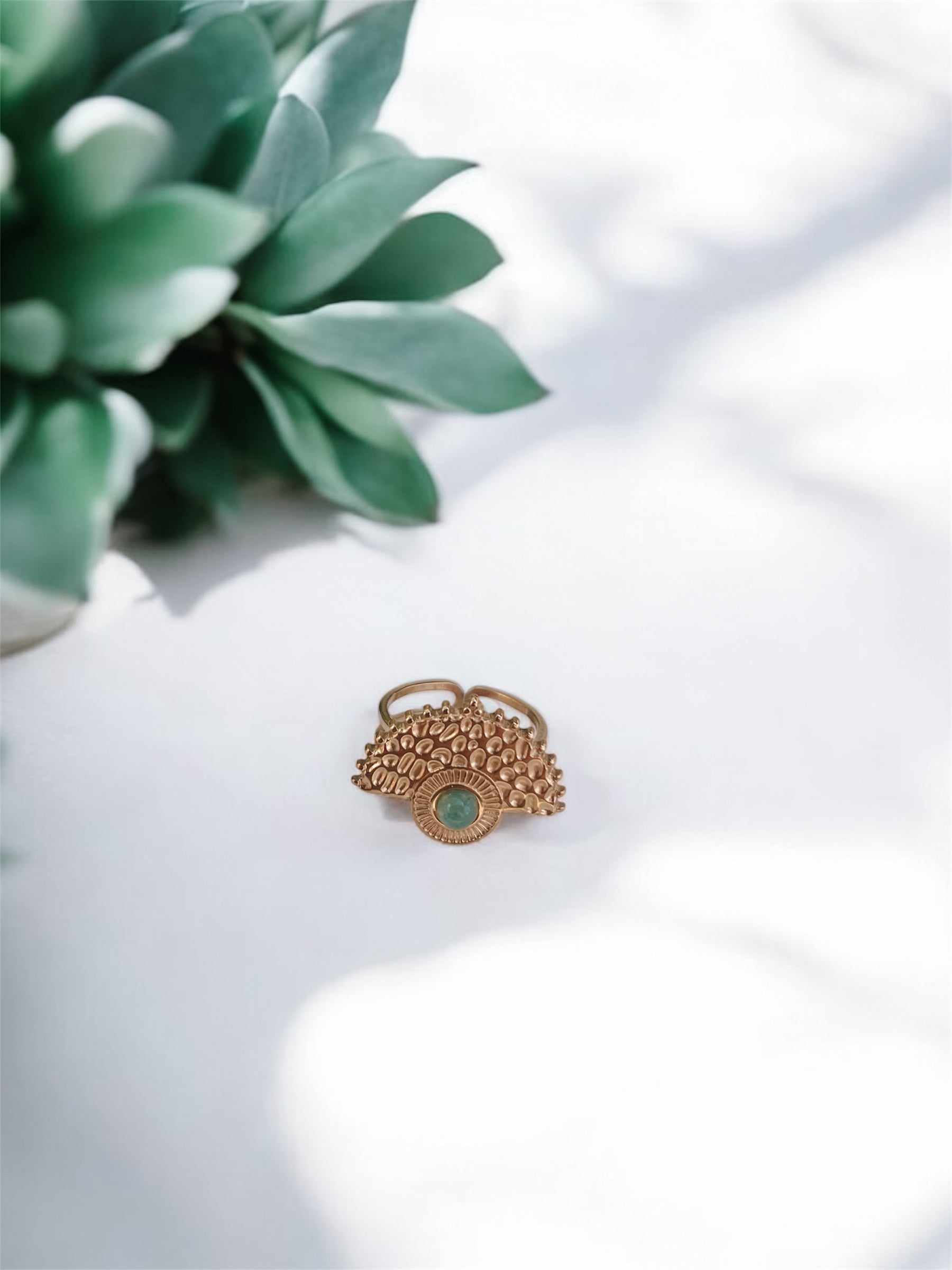 Boho Goldring mit rundem grünen Aventurin-Stein auf weißem Tisch mit Pflanze