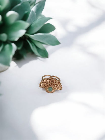 Boho Goldring mit rundem grünen Aventurin-Stein auf weißem Tisch mit Pflanze