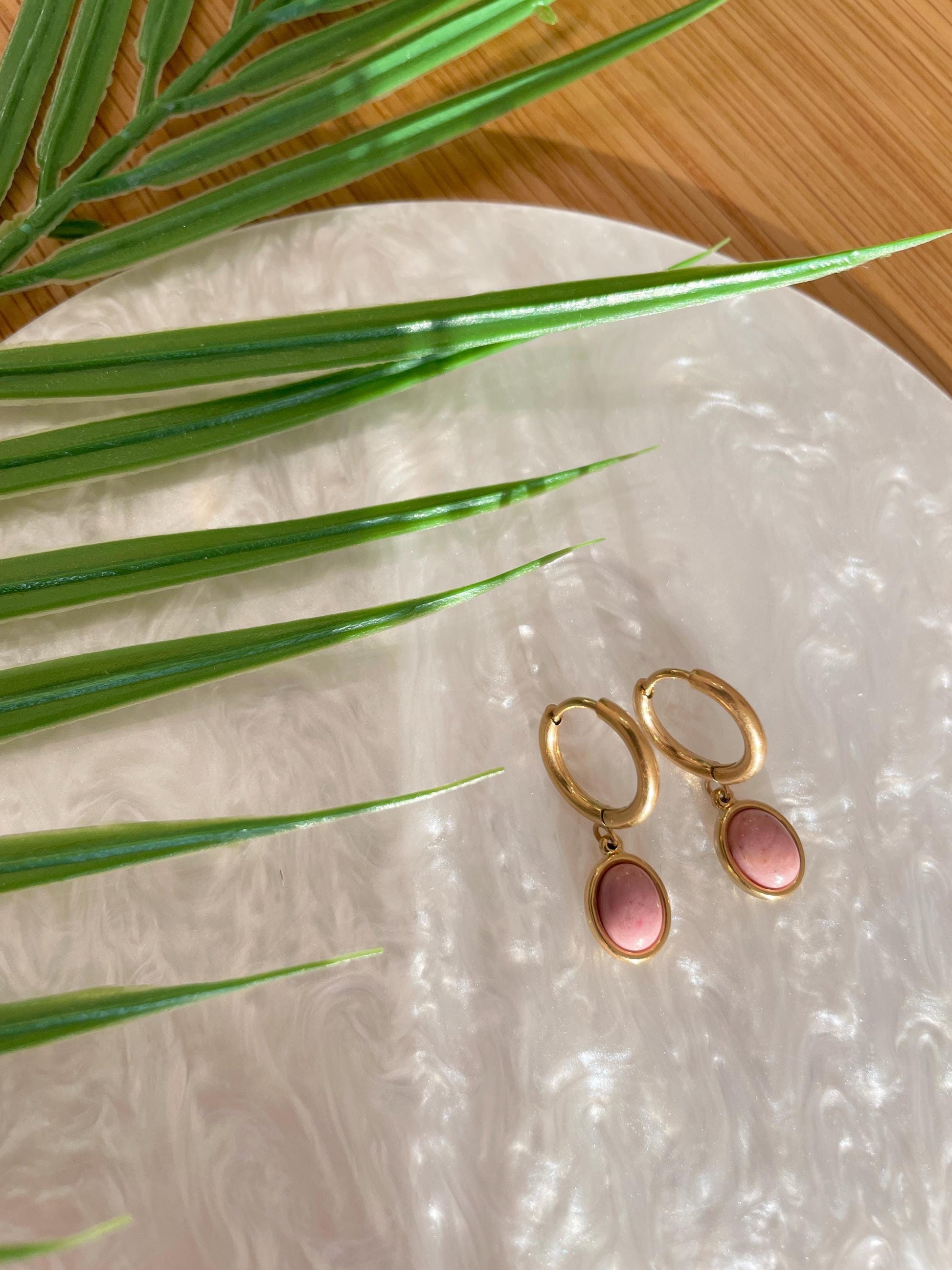 Goldene Creolen-Ohrringe mit ovalen, rosa Rhodonit-Steinen auf Tablett