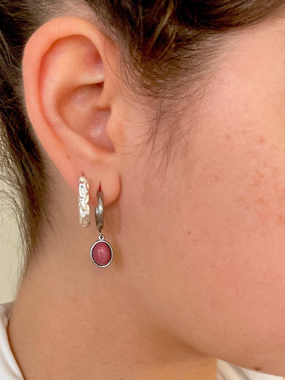 Silberne Creolen-Ohrringe mit ovalen, rosa Rhodonit-Steinen an Ohr eines Modells, Detailaufnahme