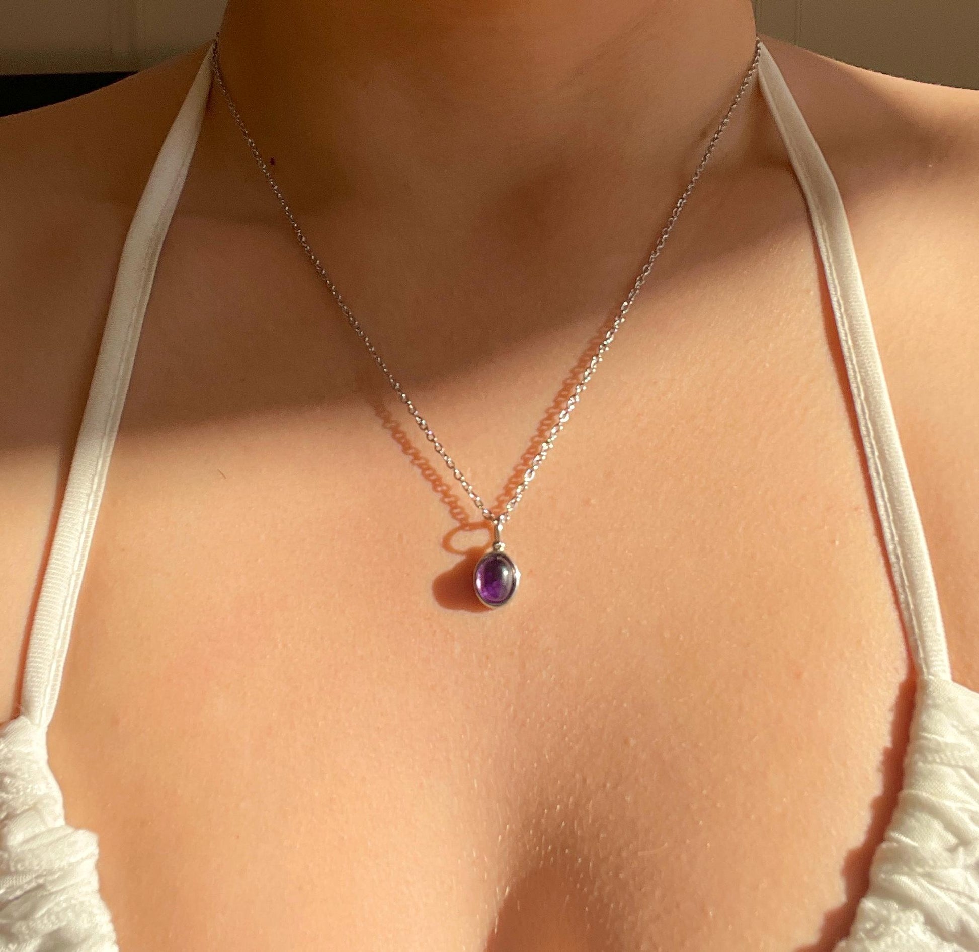 Ovaler lila Amethyst-Anhänger an feiner Silberkette, am Hals eines Modells gezeigt.