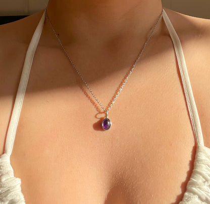Ovaler lila Amethyst-Anhänger an feiner Silberkette, am Hals eines Modells gezeigt.