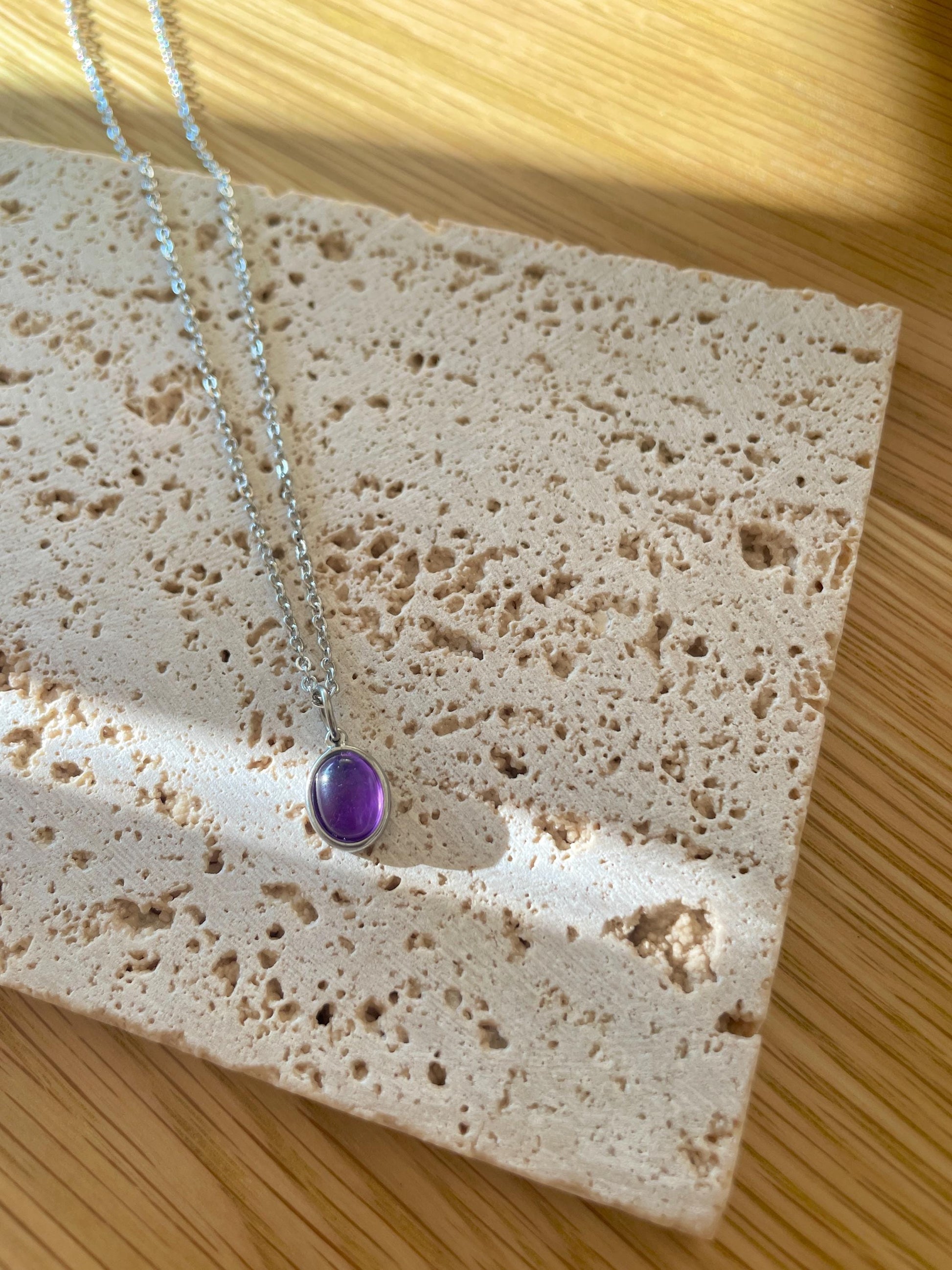 Handgemachte lila Amethyst-Kette mit ovalem Anhänger in Silber,  liegend auf Tablett