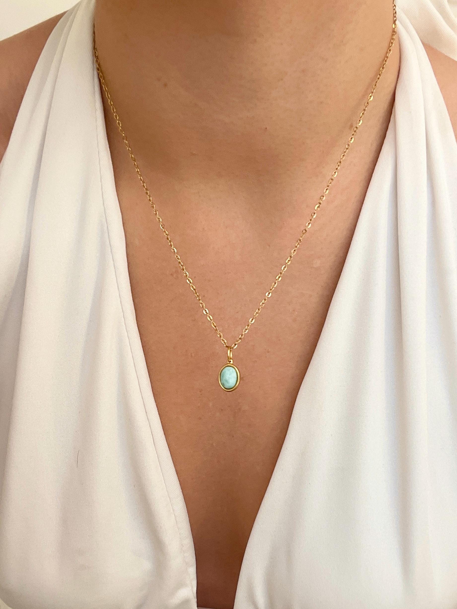 Ovaler hellhellblauer Larimar-Anhänger an feiner Goldkette, am Hals eines Modells gezeigt.