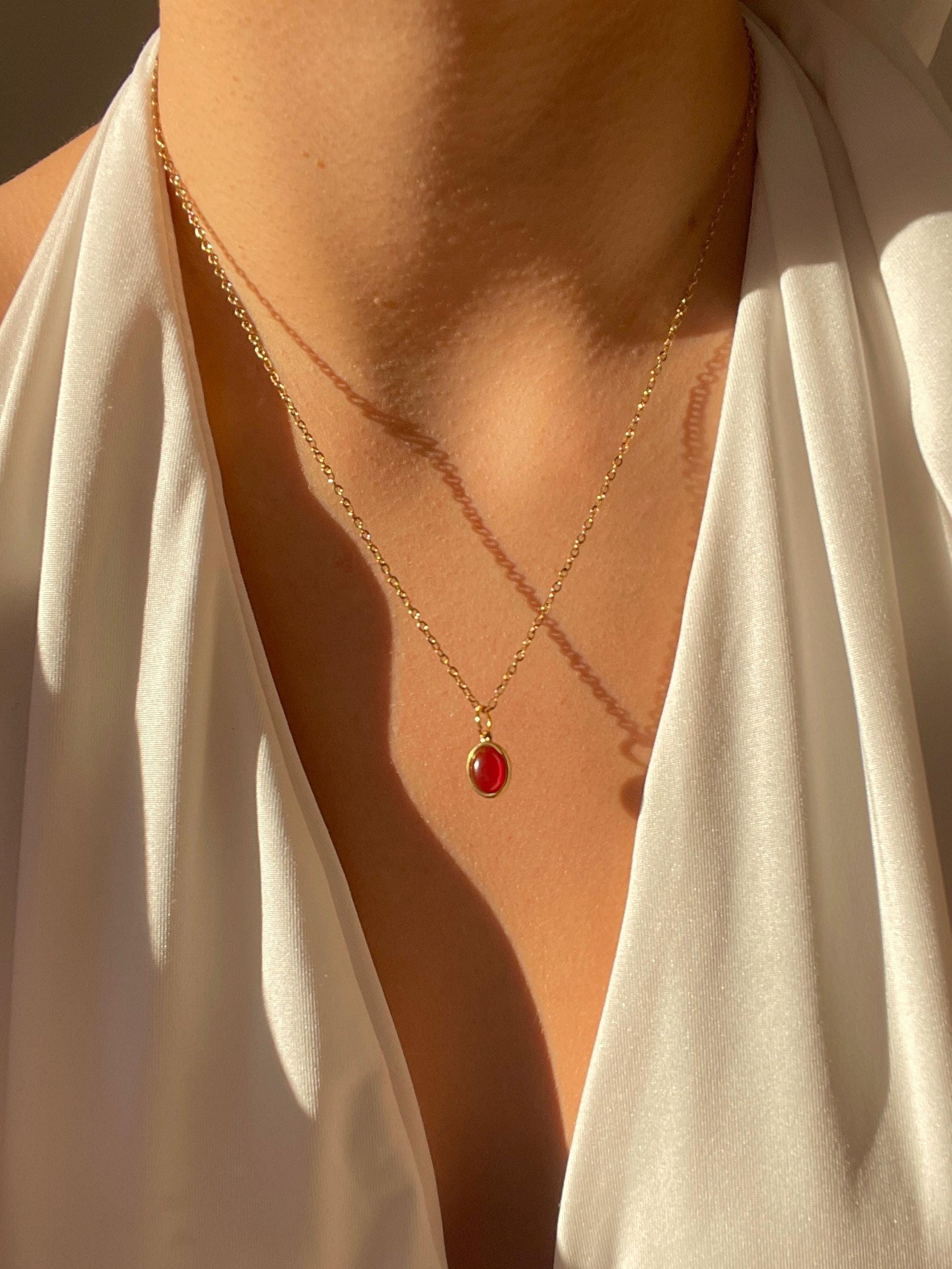 Ovaler roter Karneol-Anhänger an feiner Goldkette, am Hals eines Modells gezeigt.