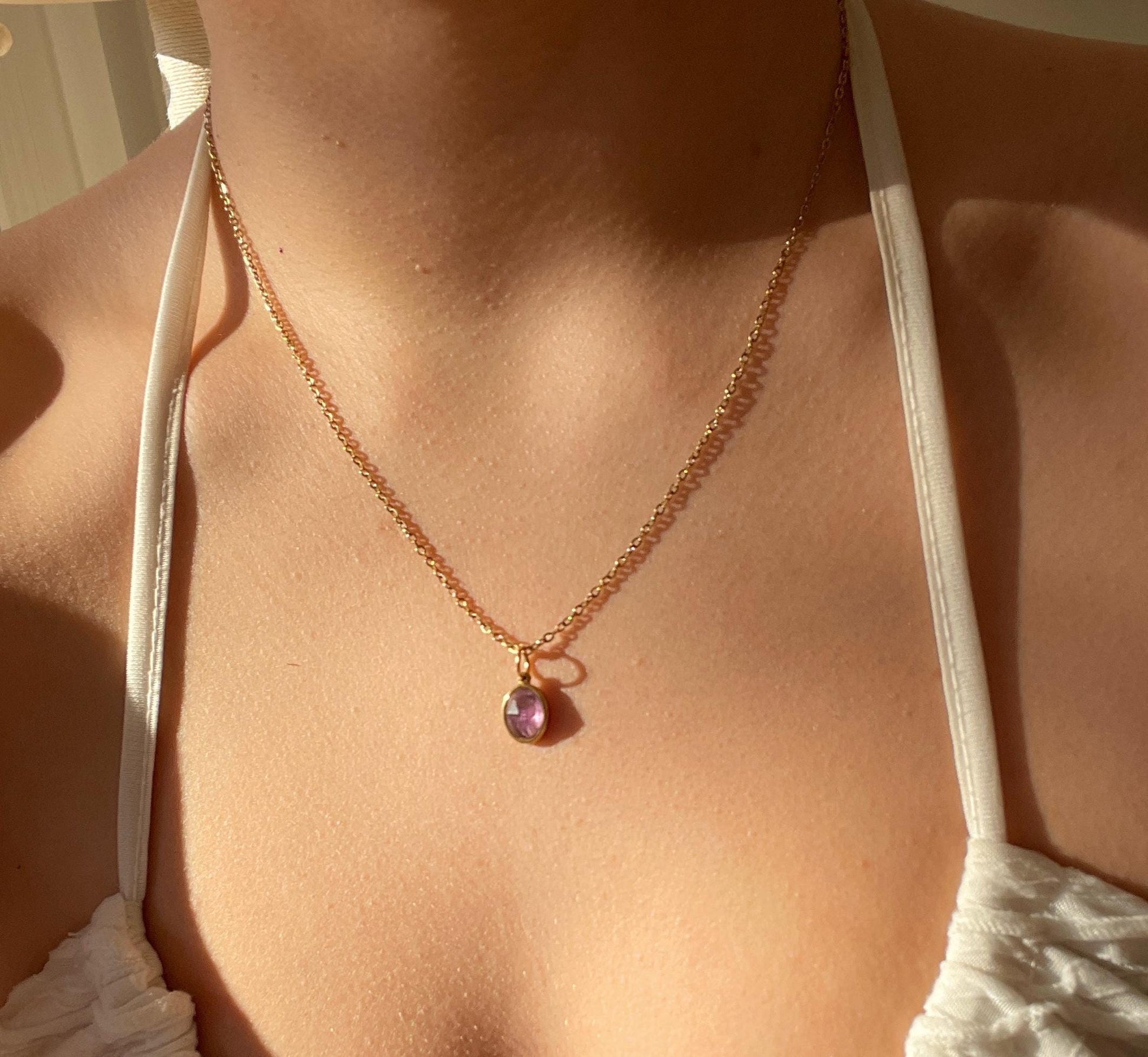 Ovaler lila Amethyst-Anhänger an feiner Goldkette, am Hals eines Modells gezeigt.