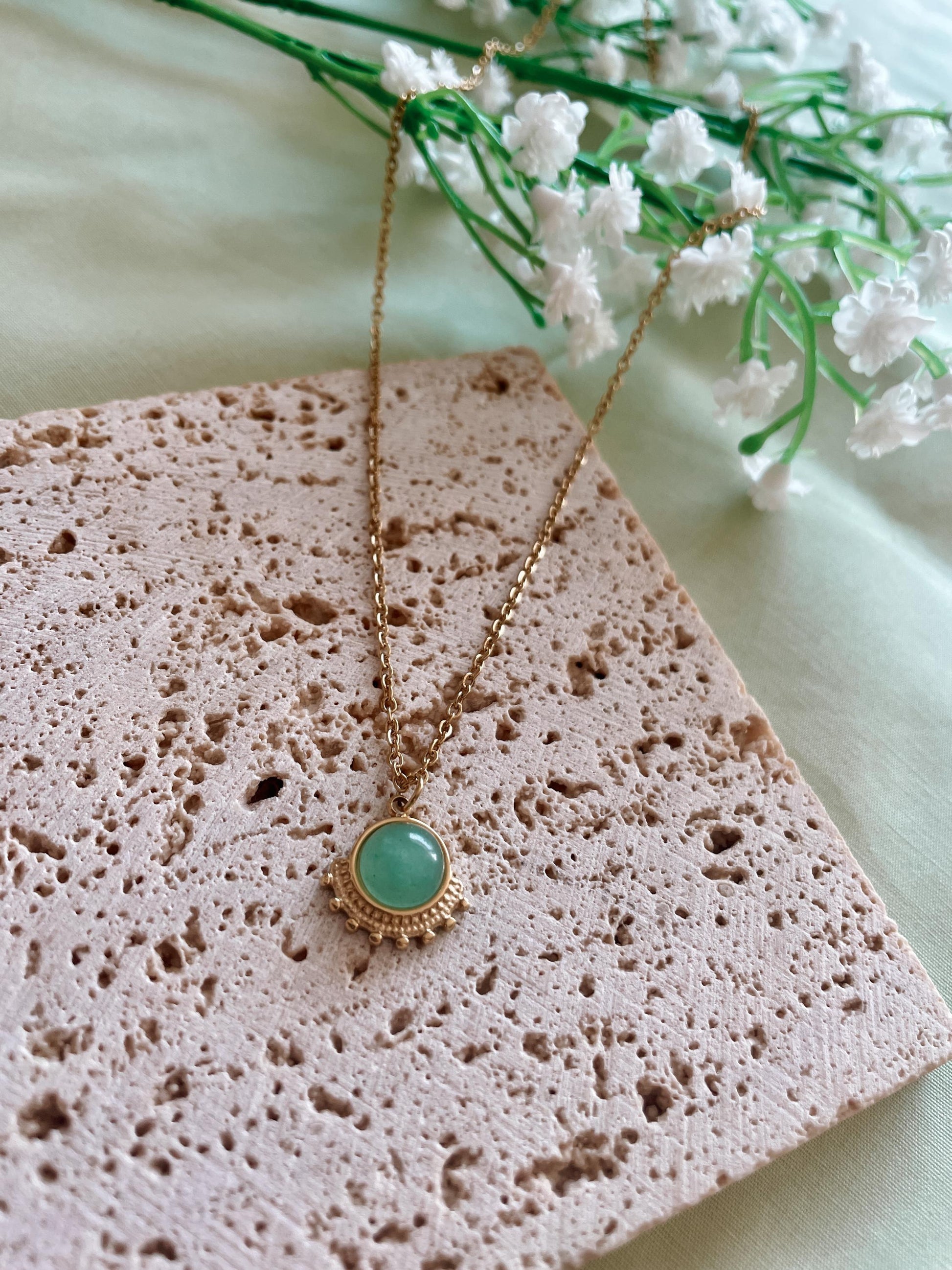 Handgemachte grüne Aventurin-Kette mit rundem Anhänger in Gold,  liegend auf Stein