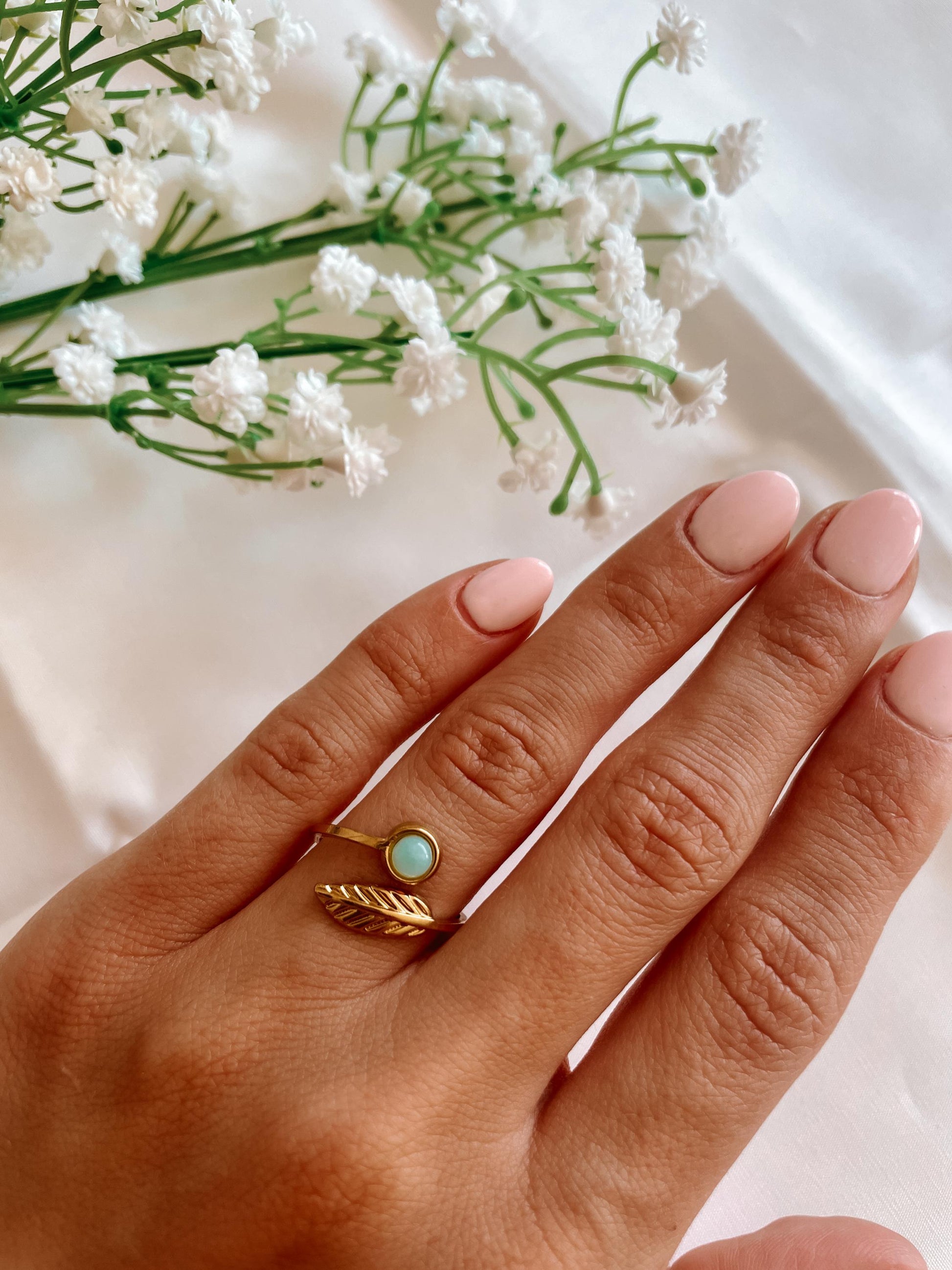 Filigraner Goldring mit rundem hellblauem Larimar-Stein und floralem Blattdesign auf Hand