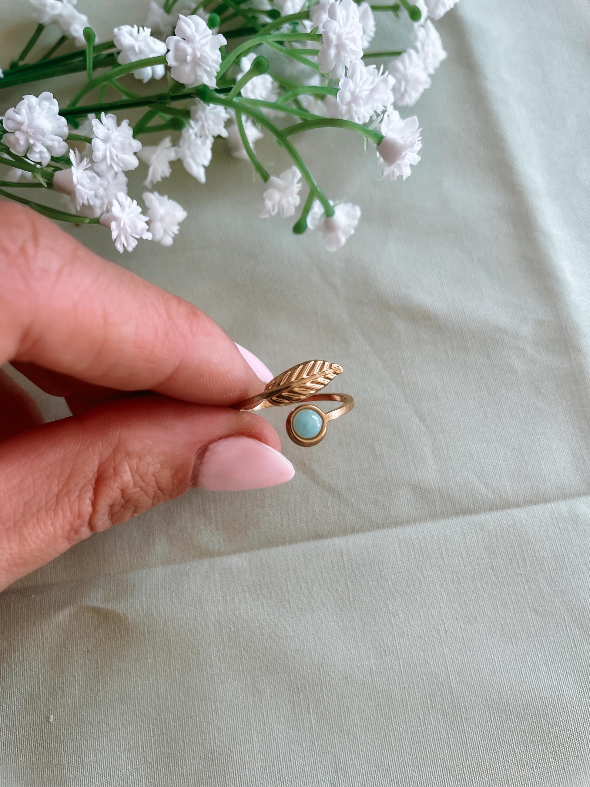Filigraner Goldring mit rundem hellblauem Larimar-Stein und floralem Blatt Design auf Tuch
