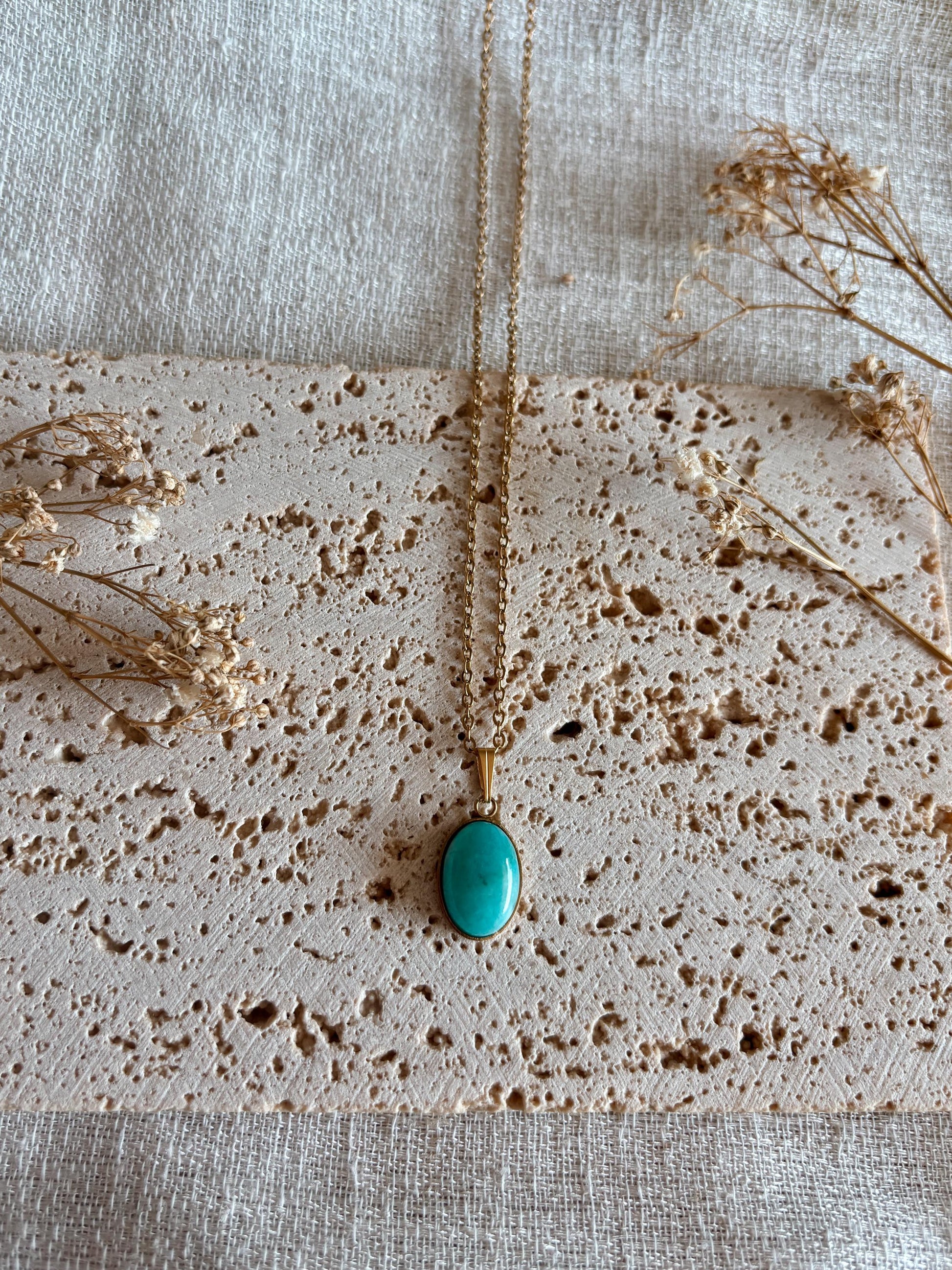 Handgemachte hellblaue Amazonit-Kette mit ovalem Anhänger in Gold,  liegend auf Tablett