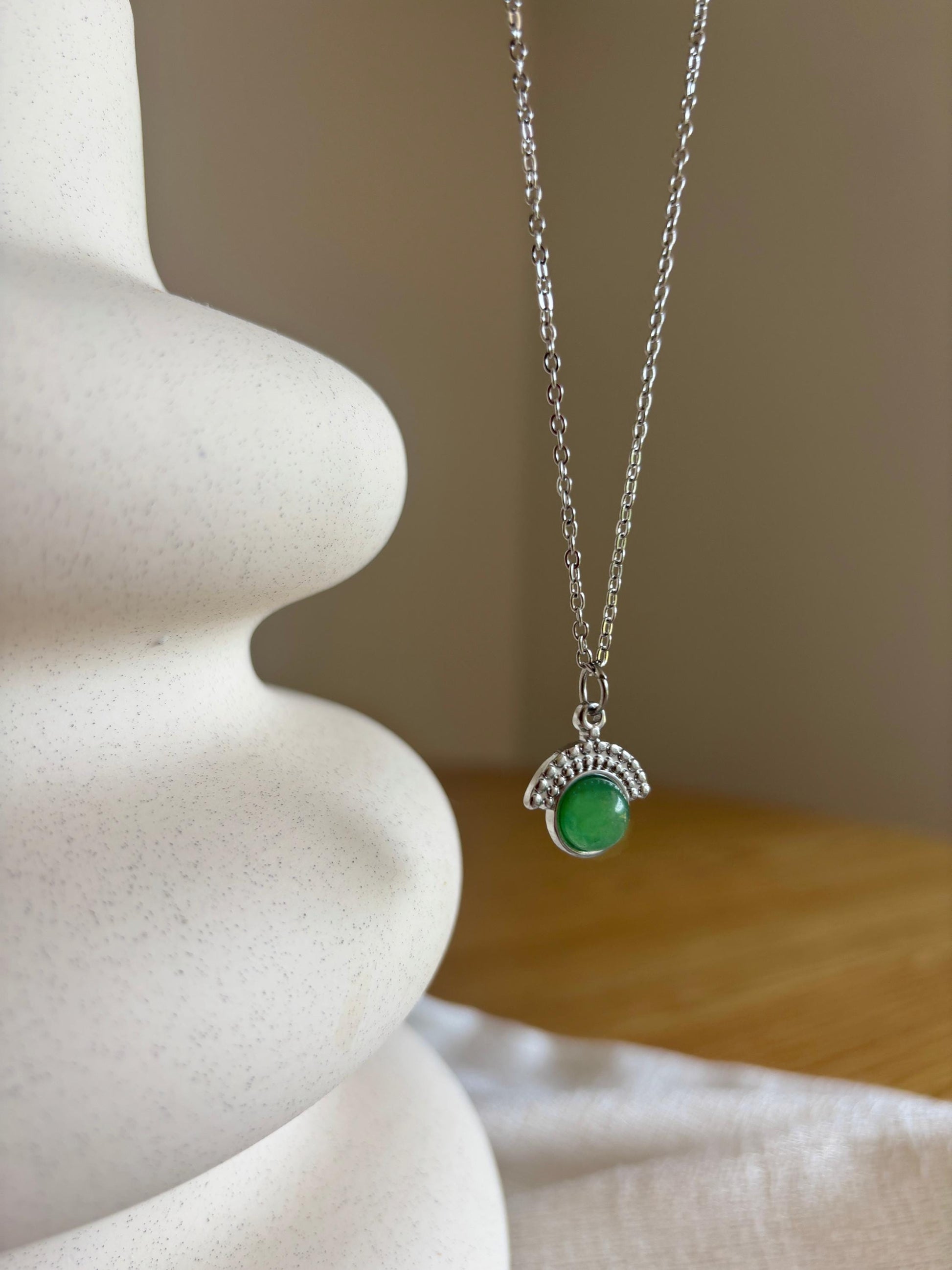 Handgemachte grüne Aventurin-Kette mit rundem Anhänger in Silber, hängend an einer Vase
