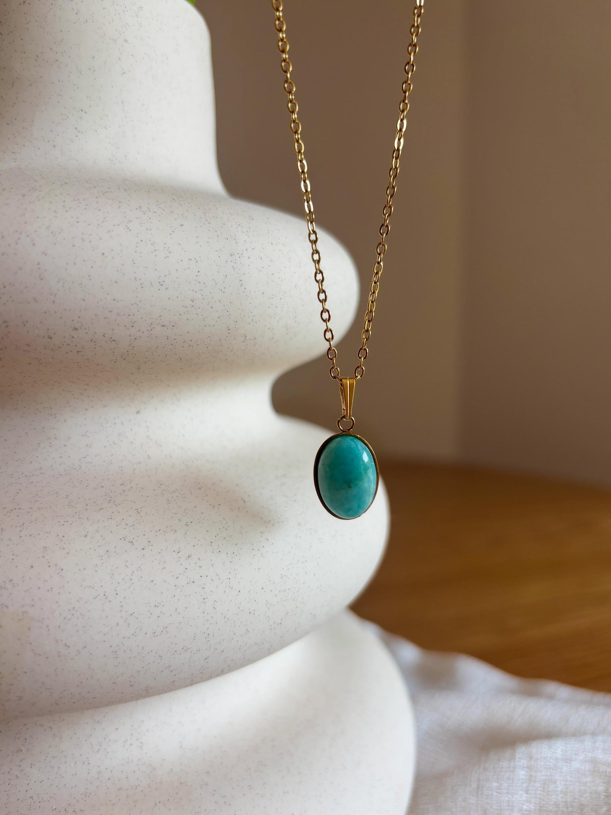 Handgemachte hellblaue Amazonit-Kette mit ovalem Anhänger in Gold, hängend an einer Vase