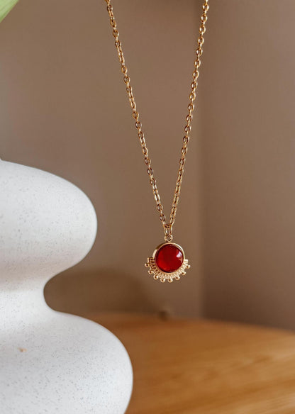 Handgemachte rote Karneol-Kette mit rundem Anhänger in Gold, hängend an einer Vase