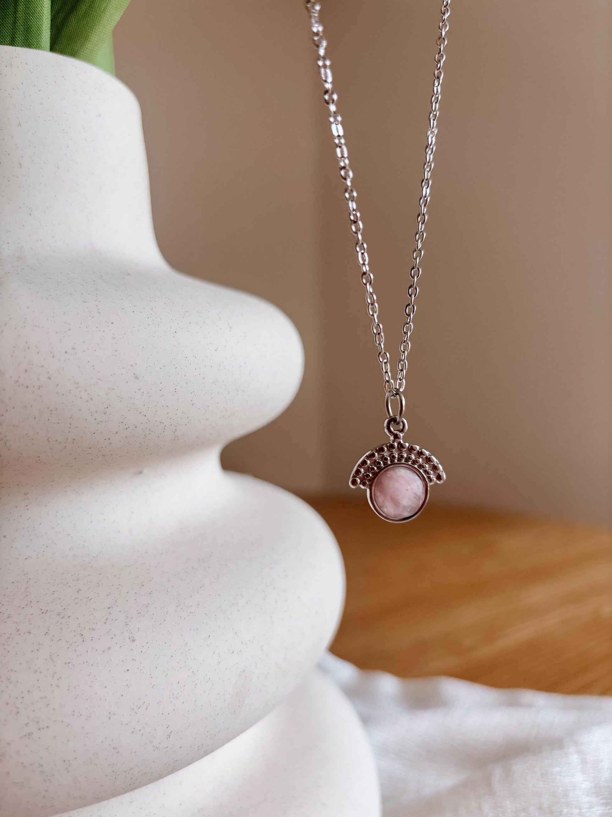 Handgemachte rosa Rosenquarz-Kette mit facettiertem Anhänger in Silber, hängend an einer Vase