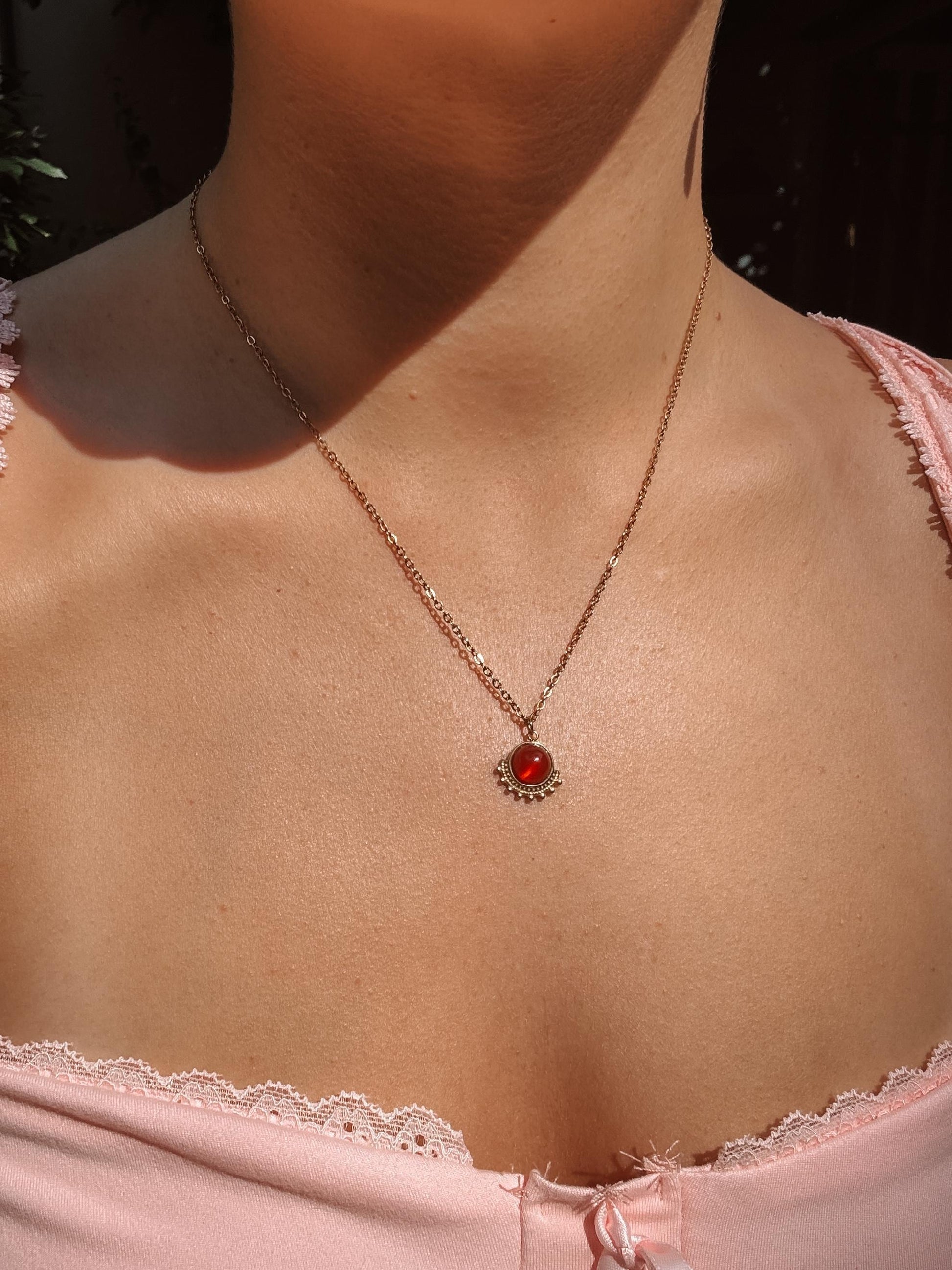 Runder roter Karneol-Anhänger an feiner Goldkette, am Hals eines Modells gezeigt.