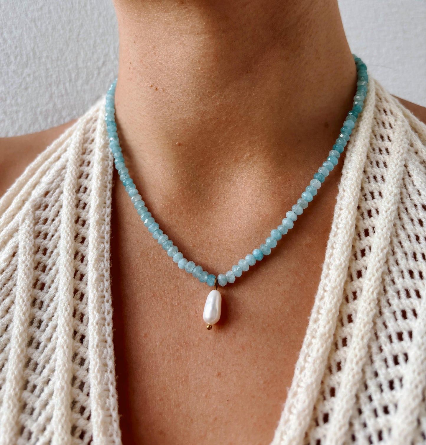 Blaue Jade-Perlenkette mit einem weißen Süßwasserperlen Anhänger am Hals eines Modells