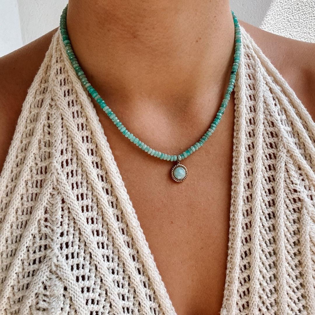 Blaue Amazonit-Perlenkette mit einem goldenen facettierten Amazonit Anhänger am Dekollete eines Modells mit Häkeltop