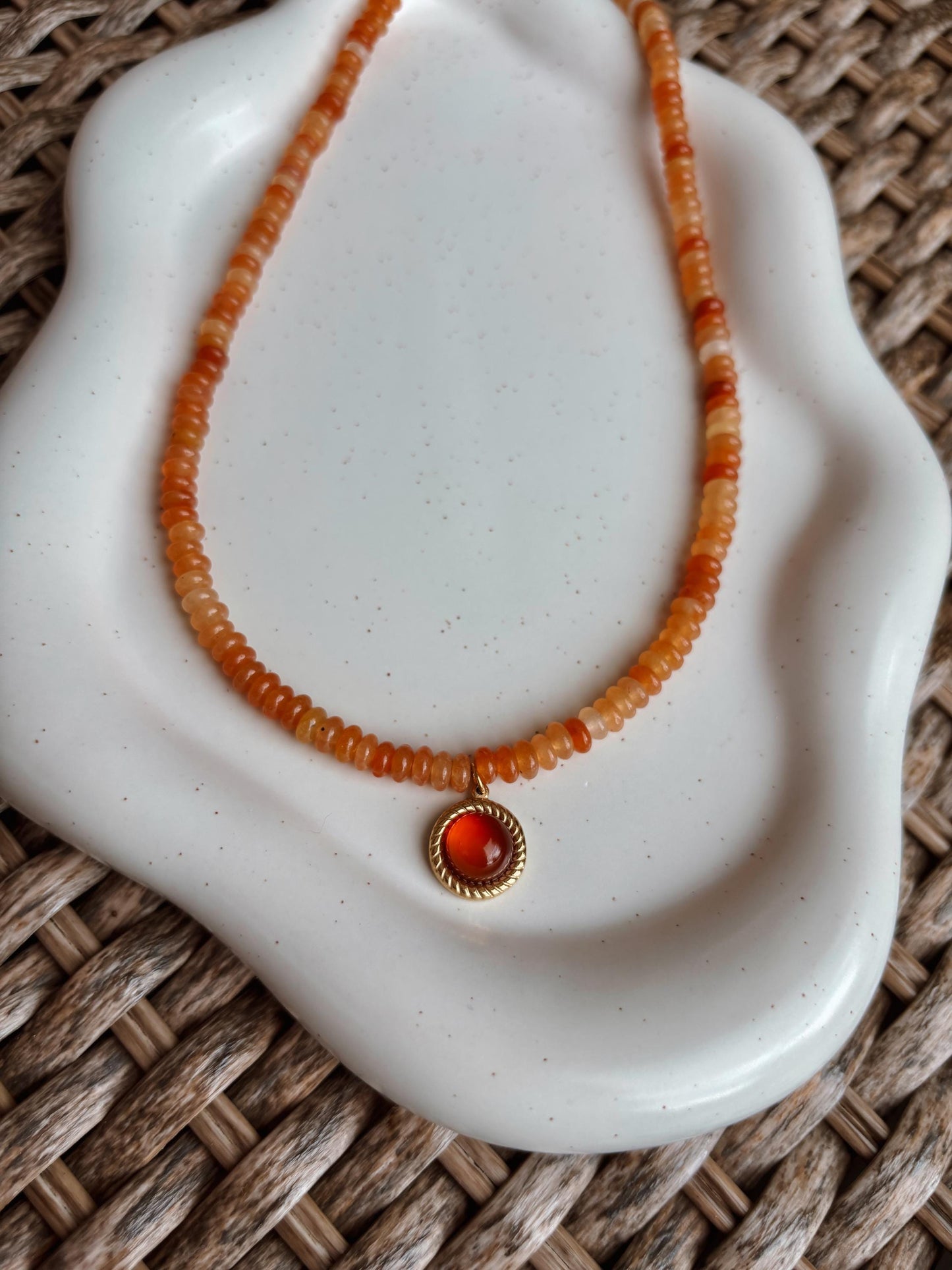 Handgemachte rote Karneol Perlen Kette mit rundem Karneol Stein Anhänger in Gold,  liegend auf Tablett